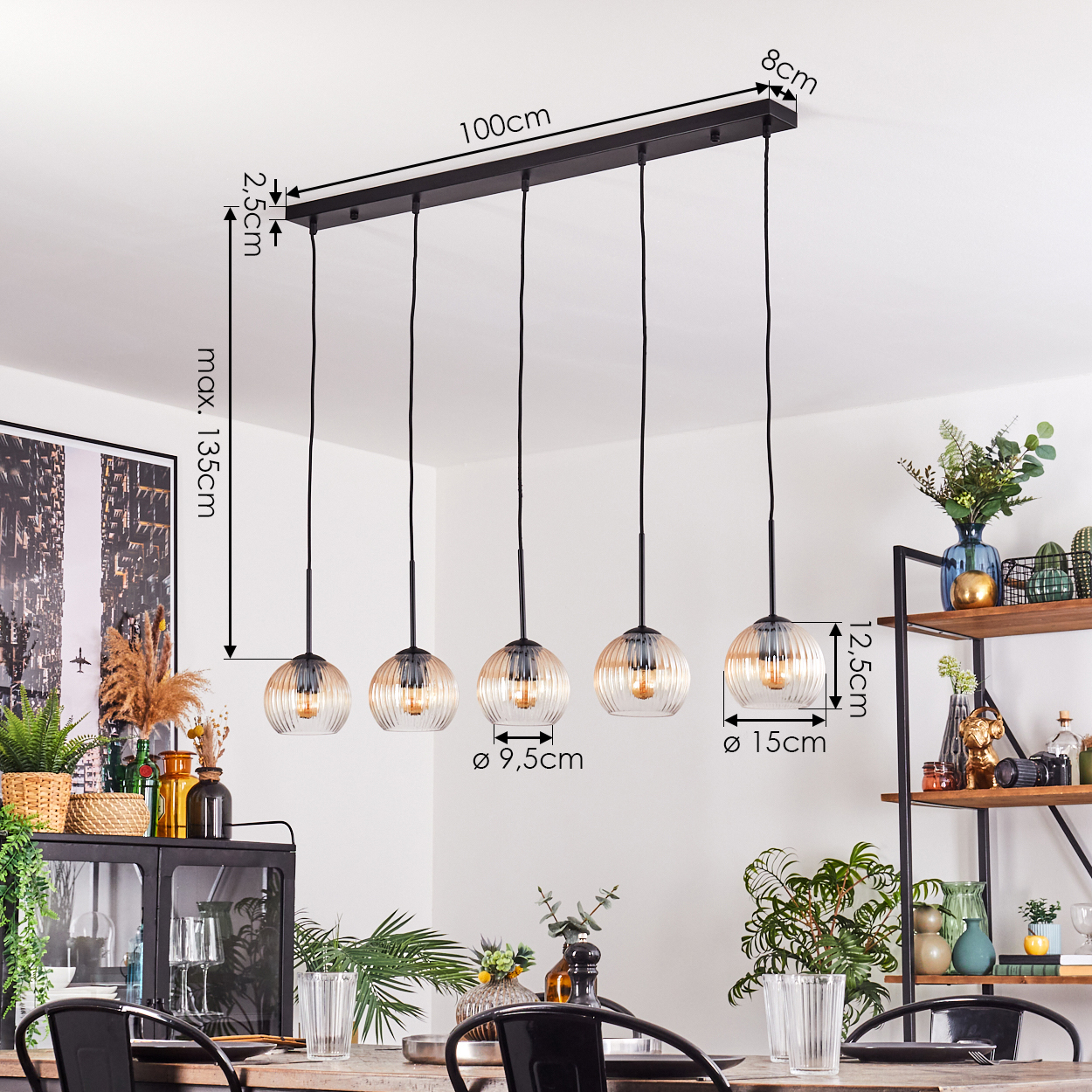 Fünf-flammige Pendelleuchte mit Glasschirmen, Maße angegeben. Esszimmer mit Pflanzen, Deko und Tisch.