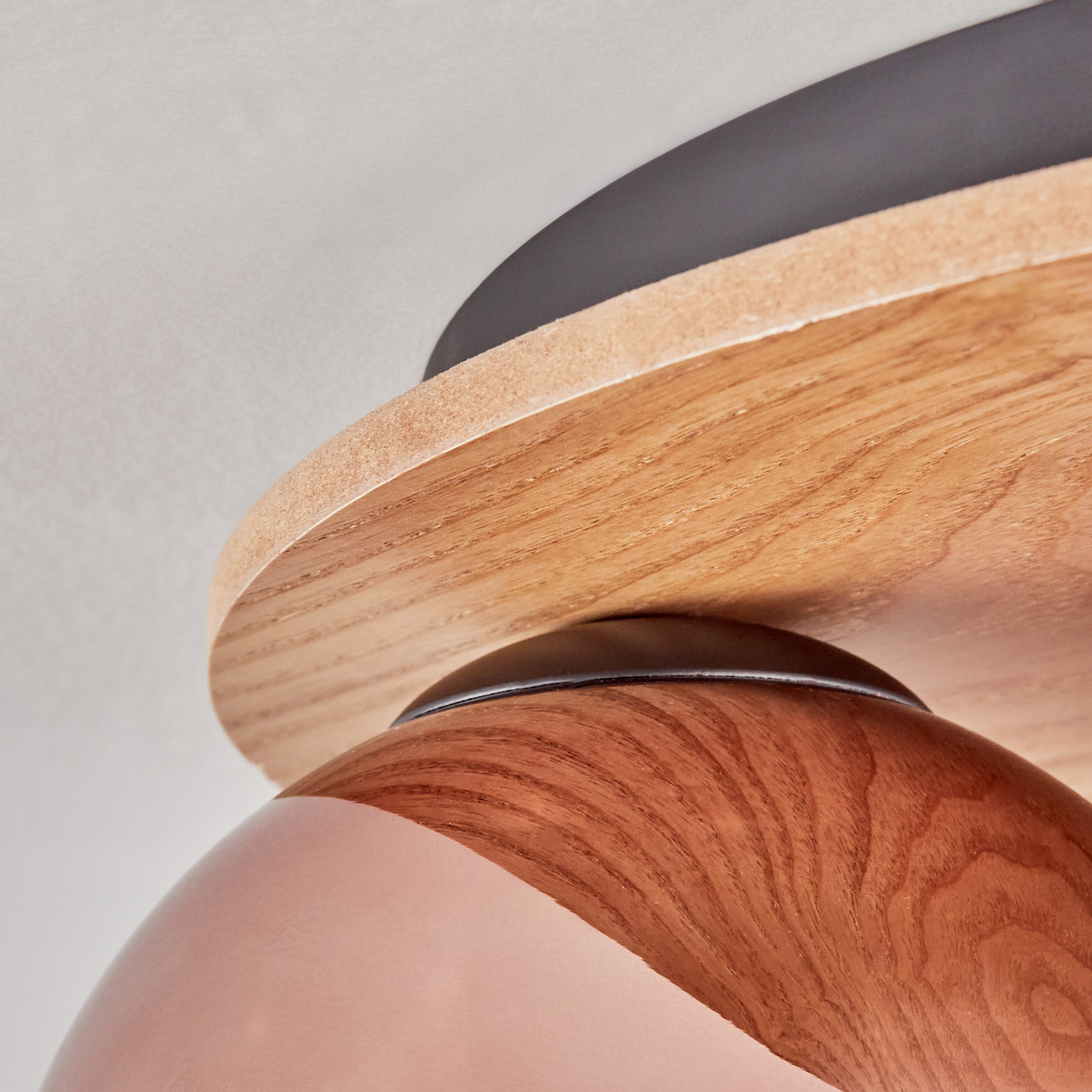 Nahaufnahme einer Holzlampenbefestigung. Die Lampe hat einen Holzschirm, einen rosa-braunen Körper und einen weißen Hintergrund.