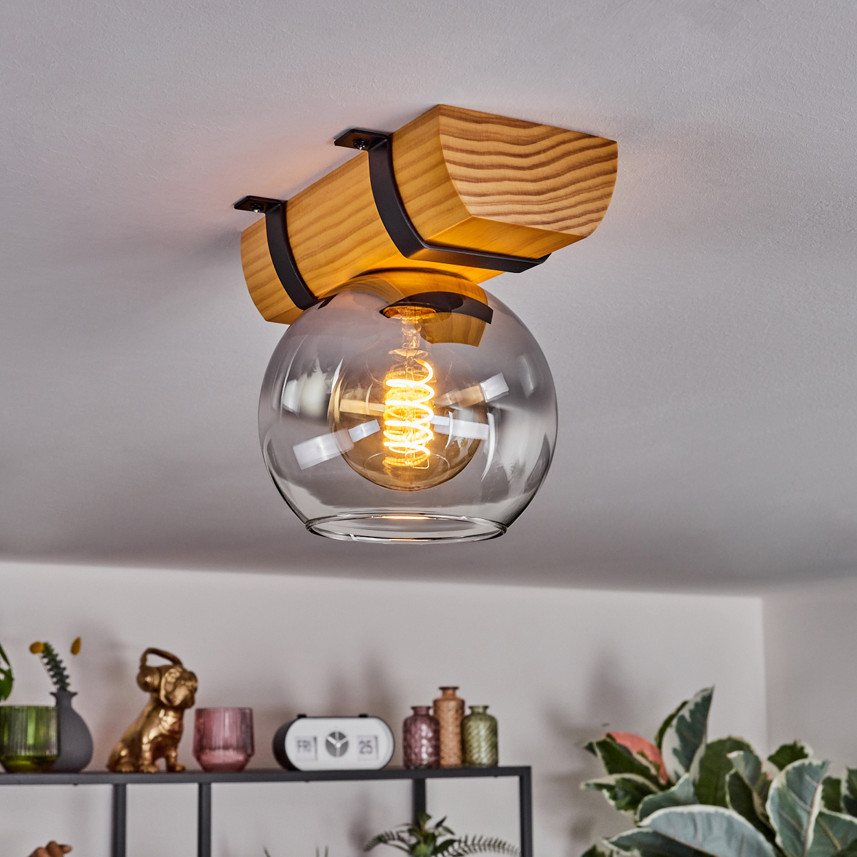 Moderne Deckenlampe mit Holzbalken und Glaskugel. Darunter ein Regal mit Dekorationsartikeln.