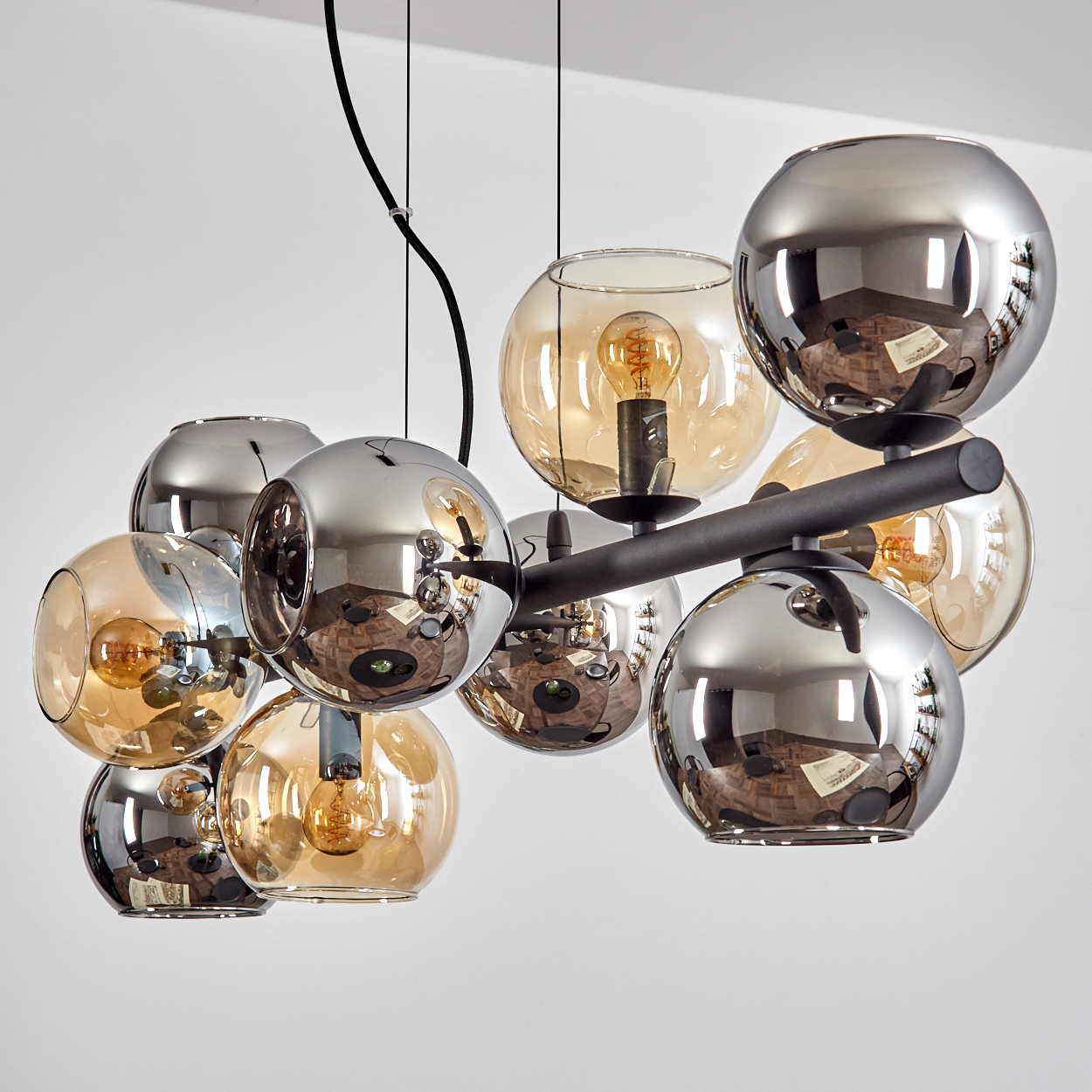 Eine moderne Hängeleuchte mit mehreren kugelförmigen Glasschirmen in Silber und Bernstein. Jede hat eine Glühbirne.
