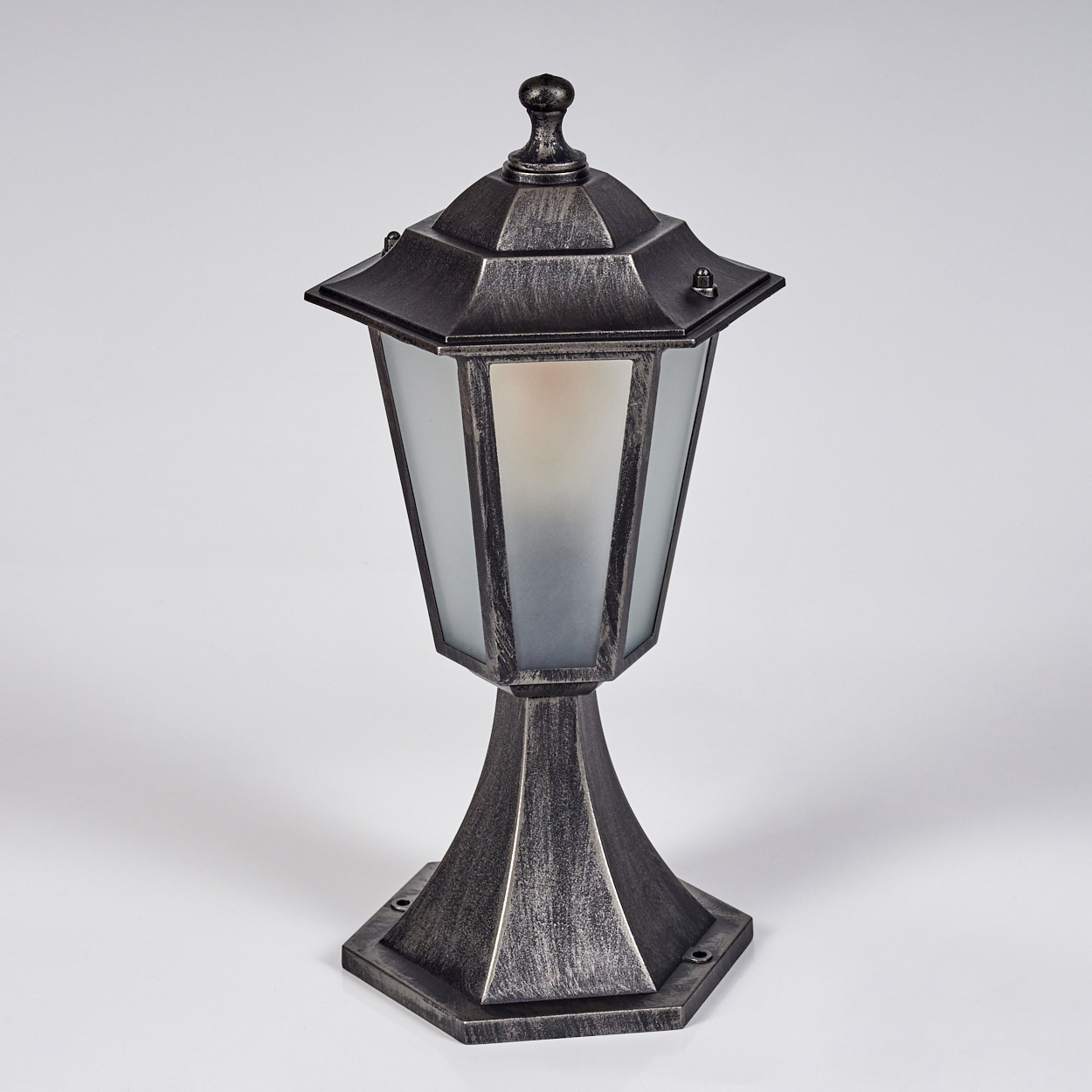 Eine dekorative Außenlampe. Sie hat eine dunkle Metalloberfläche und ein Milchglasgehäuse. Die Lampe steht auf weißem Hintergrund.