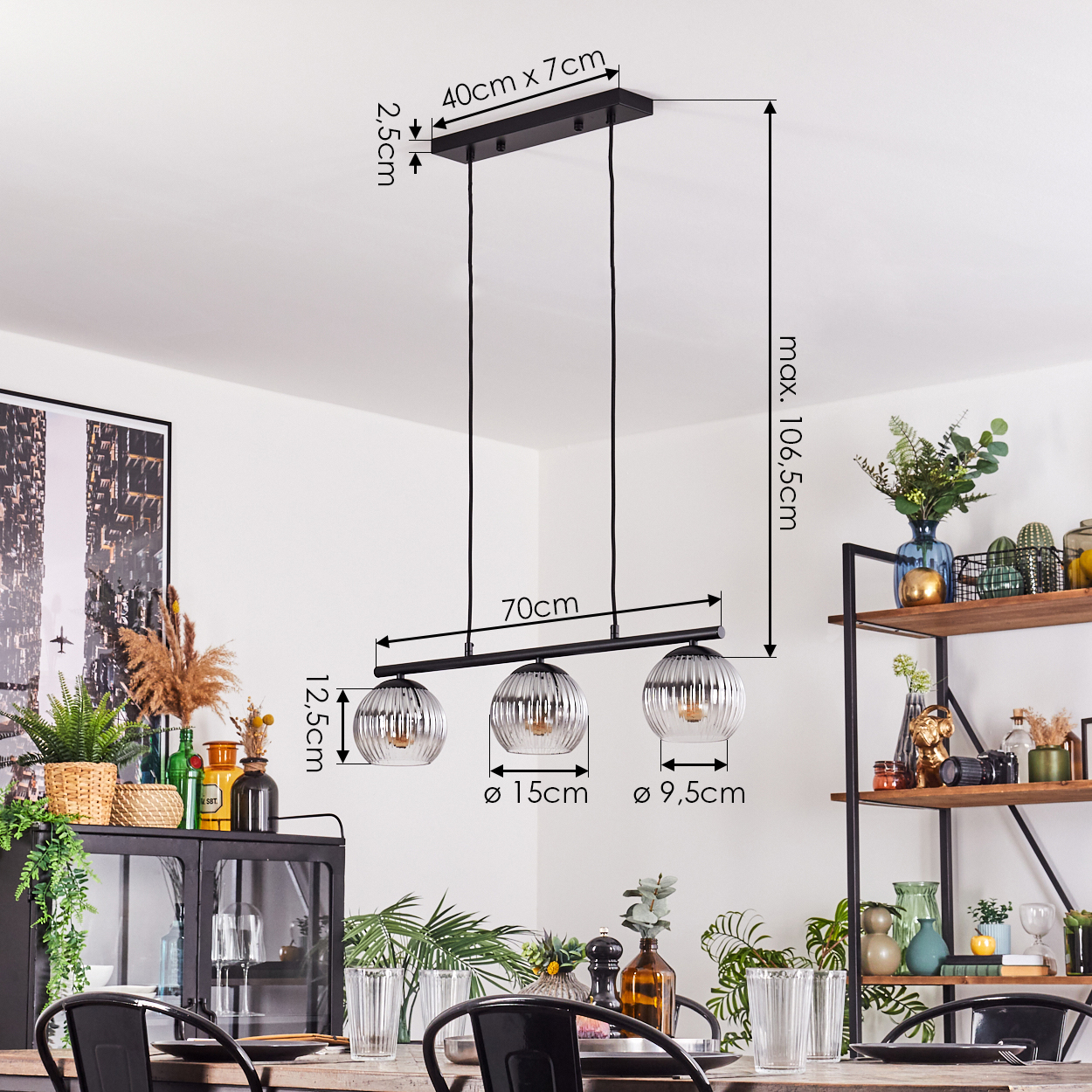 Ein modernes Esszimmer mit einem schwarzen Kronleuchter mit drei Glaslampen. Es gibt einen Esstisch und Regale mit Dekoration.