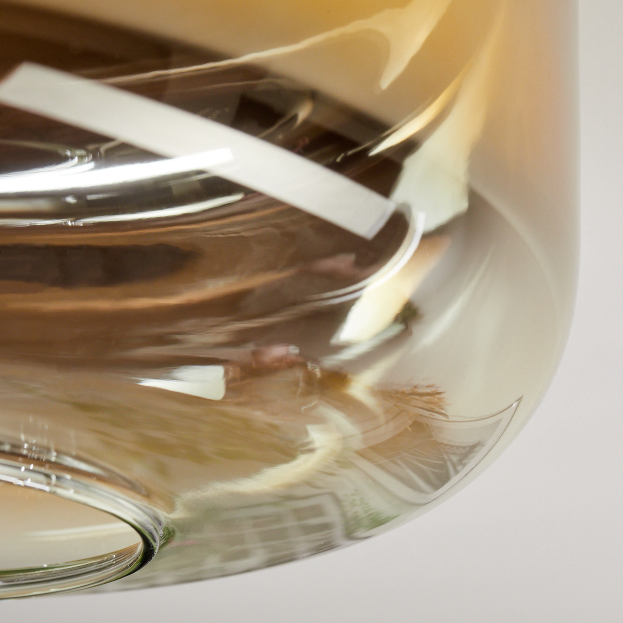 Nahaufnahme eines Glasobjekts mit weißem Etikett. Das Glas hat goldene und braune Farbtöne. Der Hintergrund ist weiß.