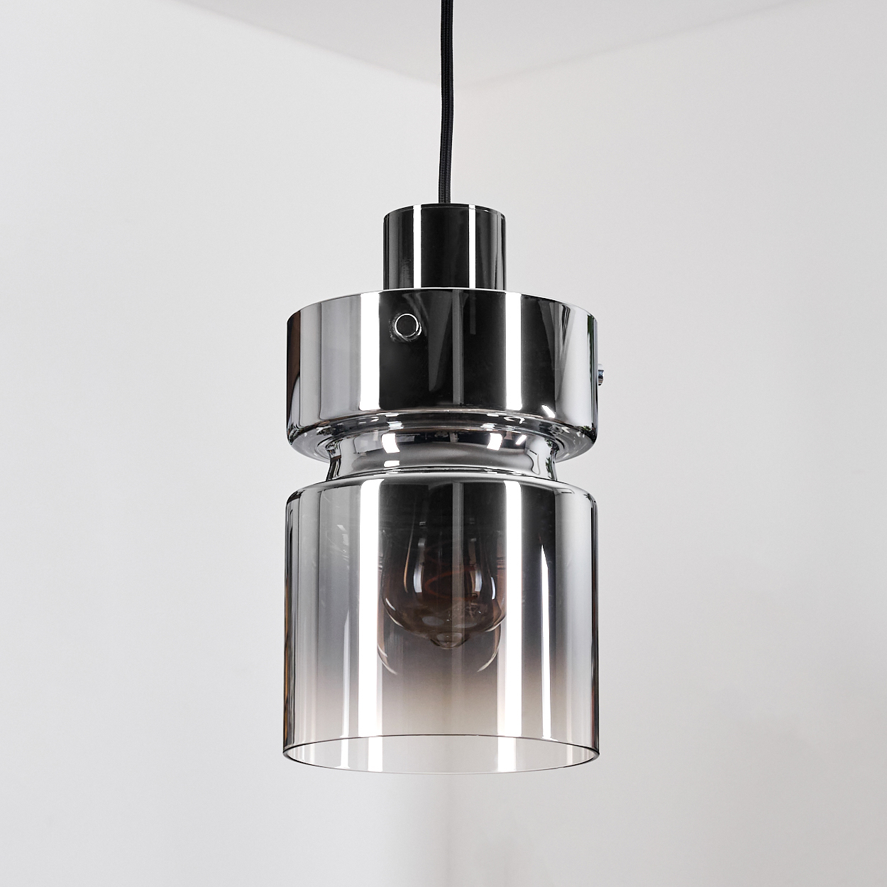 Eine moderne Pendelleuchte aus Chrom und Glas hängt von der Decke. Der Glasschirm hat einen Farbverlauf, und eine Edison-Glühbirne ist sichtbar.