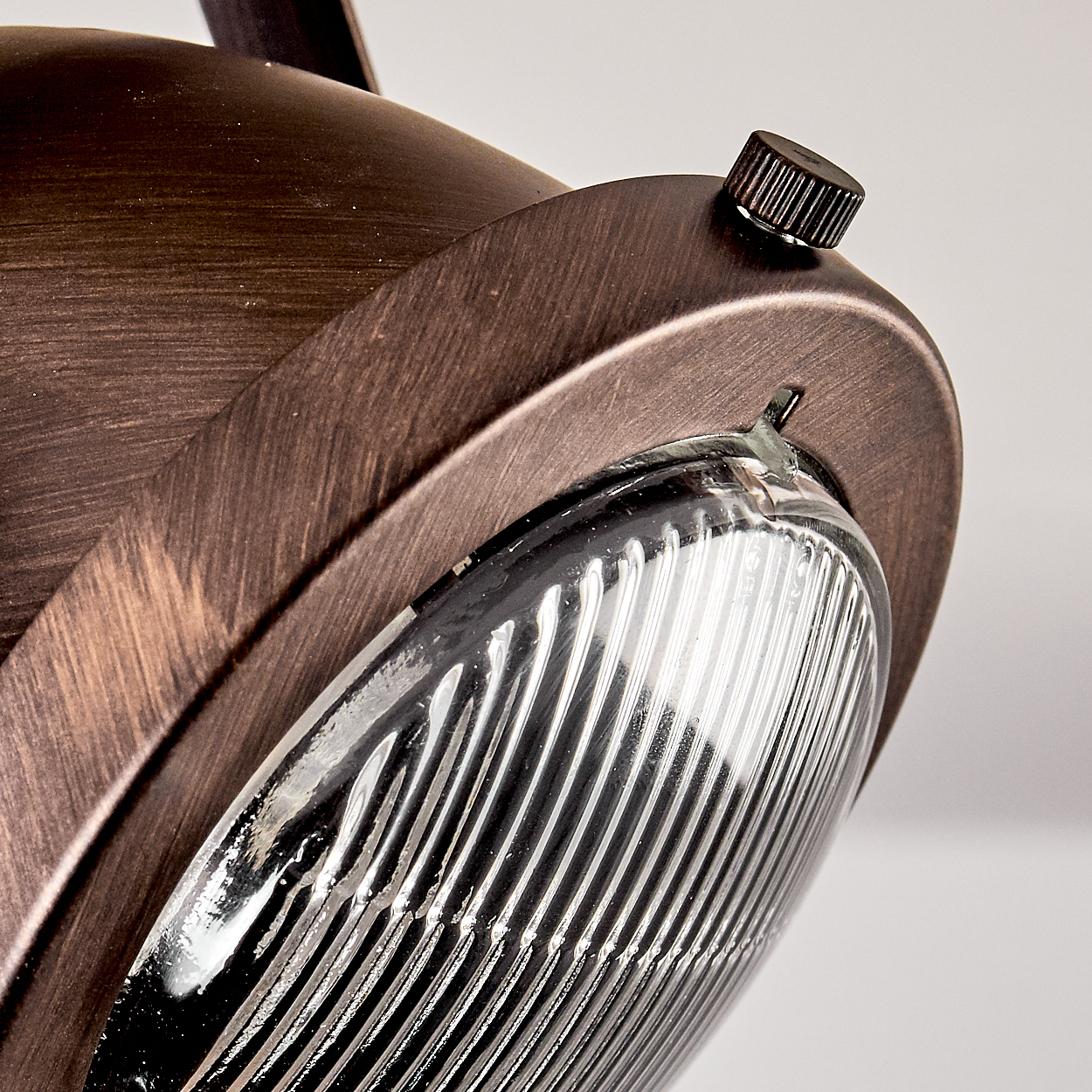 Nahaufnahme einer braunen Vintage-Lampe. Sie hat eine geriffelte Glaslinse und einen metallischen, strukturierten Körper. Oben befindet sich ein kleiner Knopf.