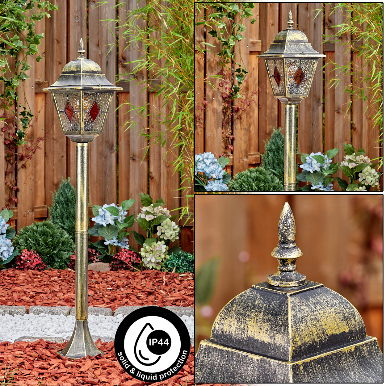 Eine goldene Außenlampe mit dekorativer Spitze steht in einem Garten. Im Hintergrund sind Holzzaun und Pflanzen zu sehen.