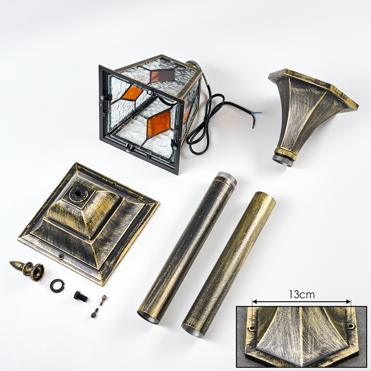 Zerlegte Laternenbestandteile auf Weiß. Enthält Lampe, Sockel, Stangen und Dekorationselemente. Die Lampe hat Buntglas.