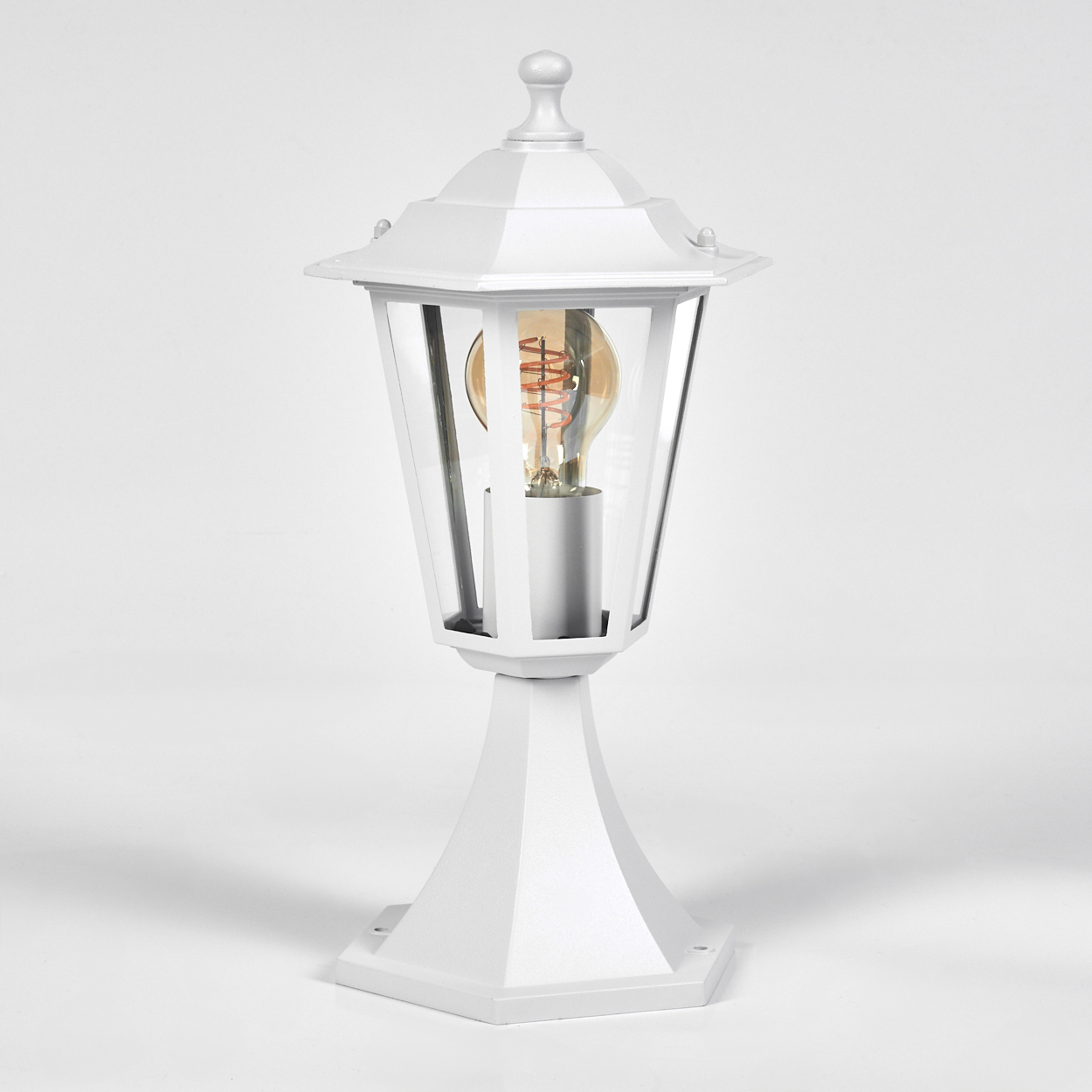Eine weiße Außenlampe auf weißem Hintergrund. Sie hat ein Glasgehäuse und eine sichtbare Glühbirne.