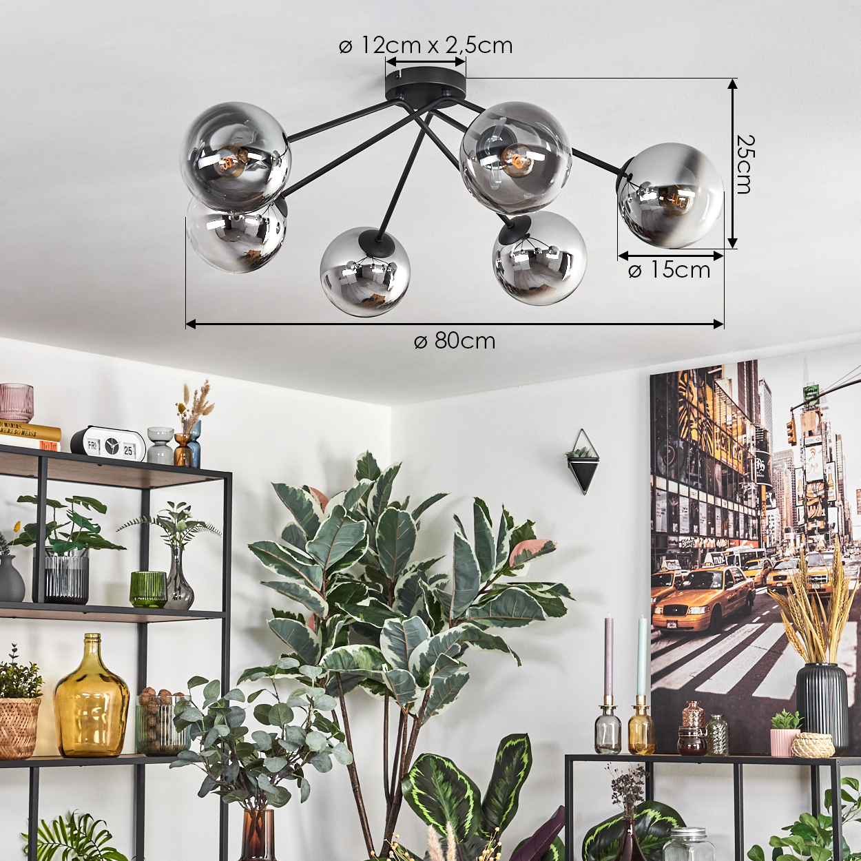 Eine moderne Deckenleuchte mit sechs silbernen Kugeln hängt über Pflanzen und Regalen. Ein Stadtbildgemälde hängt an der Wand.
