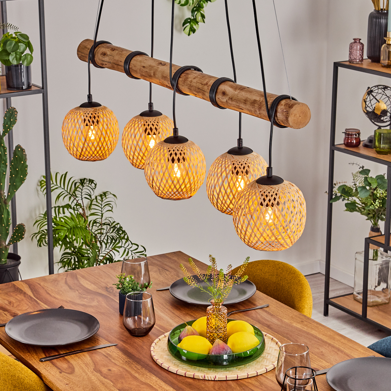 Ein Esszimmer mit Holztisch, Leuchte mit gewebten Schirmen und Schale mit Zitronen.
