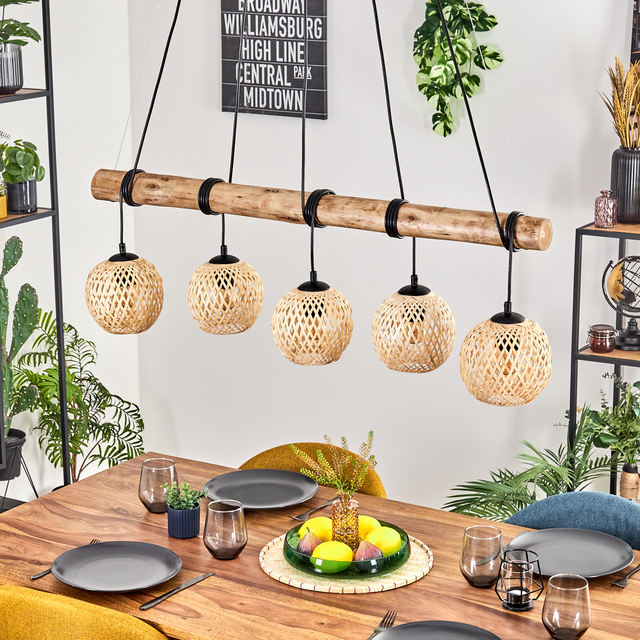 Ein Esstisch mit Tellern, Gläsern und einem Centerpiece. Ein Holzbalken mit hängenden gewebten Lampen.