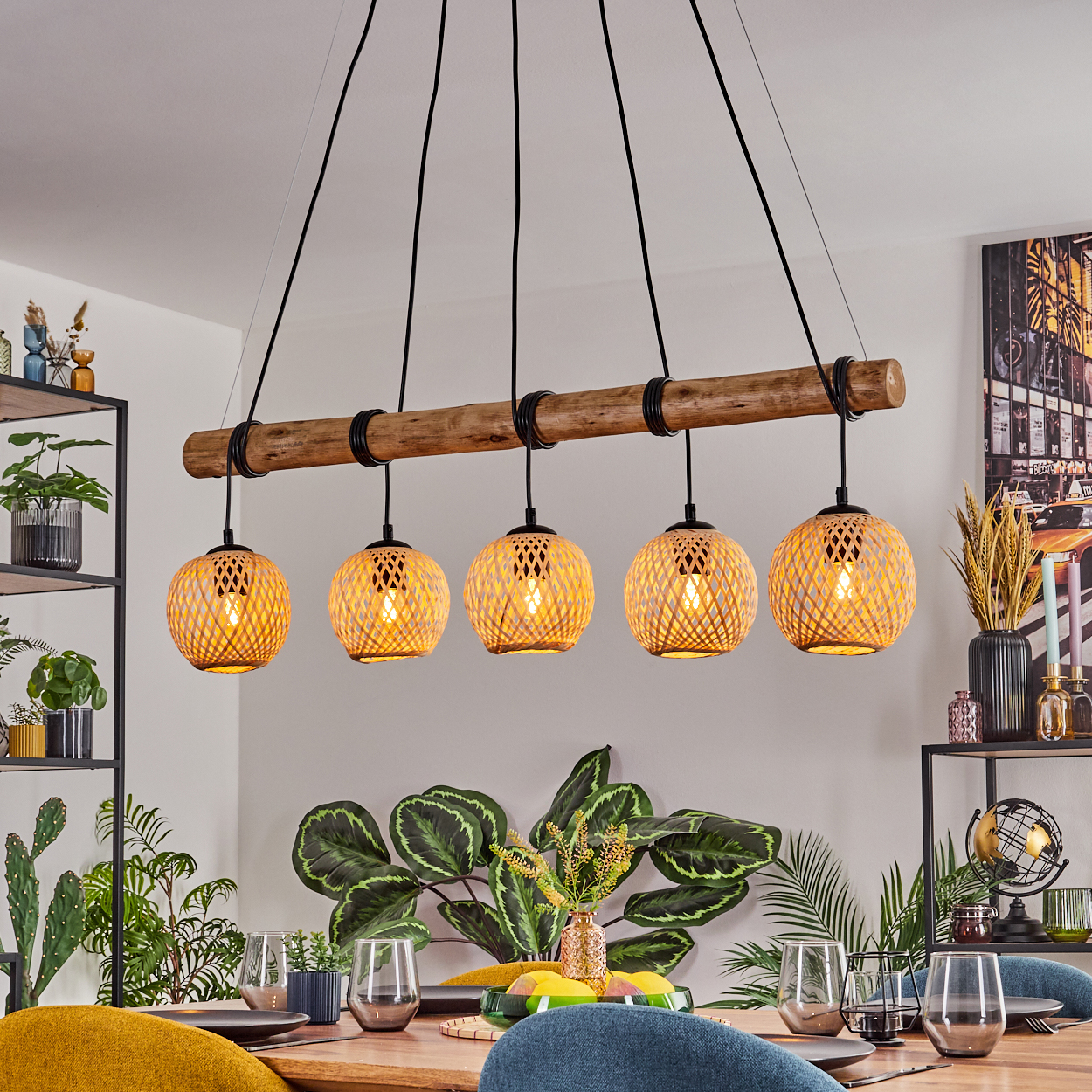 Esszimmer mit Holzbalken-Kronleuchter. Fünf gewebte Lampen hängen über einem Holztisch mit Gläsern, Pflanzen und einem schwarzen Metallregal.