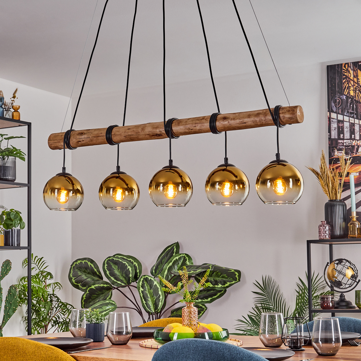 Esszimmer mit Holztisch, Hängelampen, Pflanzen und Glaswaren. Ein modernes, helles Interieur.