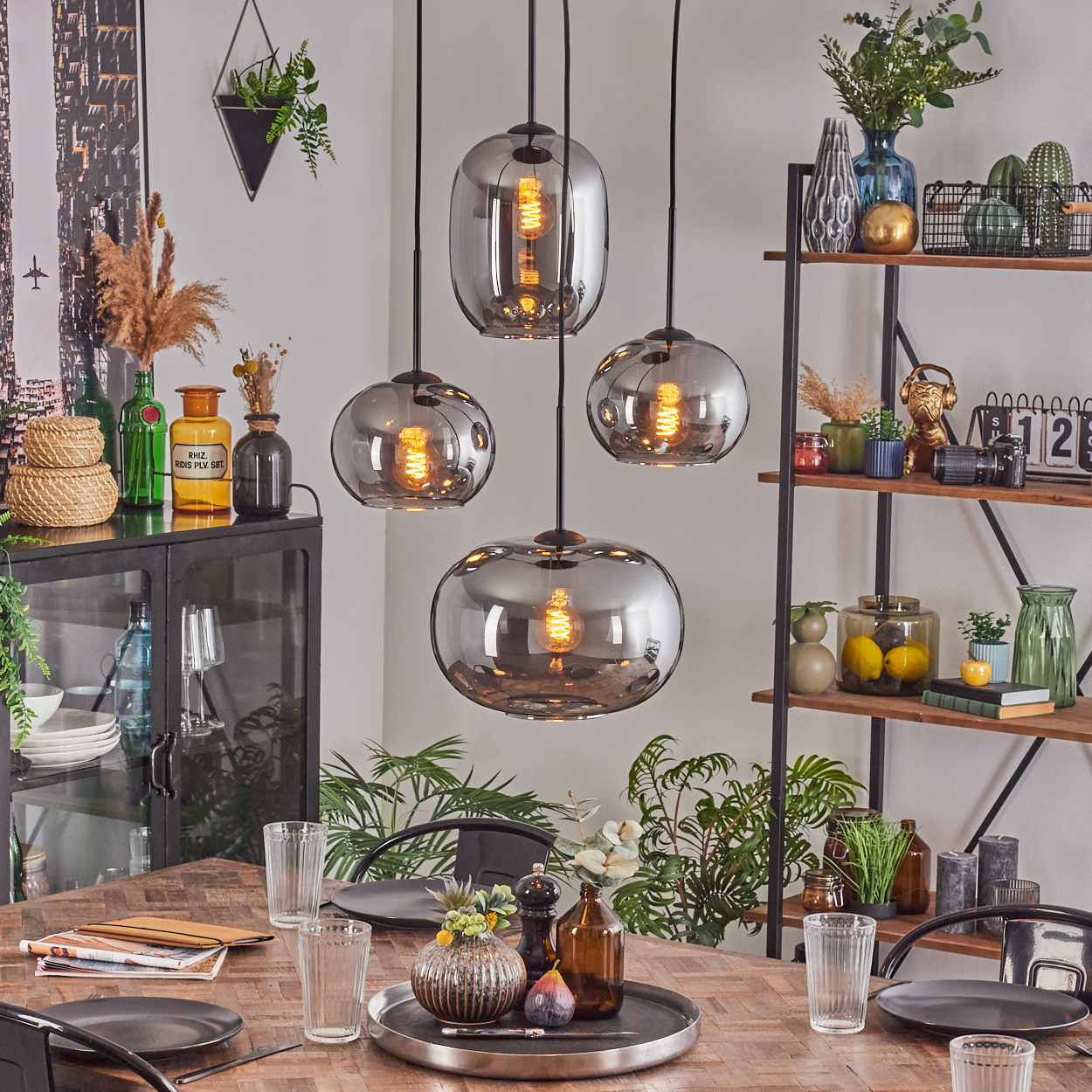 Ein Esszimmer mit Holztisch, Hängelampen und verschiedenen Dekorationsartikeln auf Regalen und dem Tisch selbst.