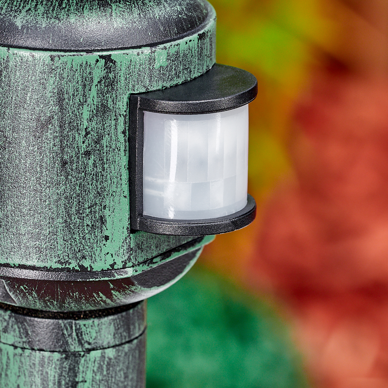 Nahaufnahme eines grün-schwarzen Sensors. Der Sensor ist vor einem verschwommenen Hintergrund aus grünen, gelben und roten Farben angeordnet.