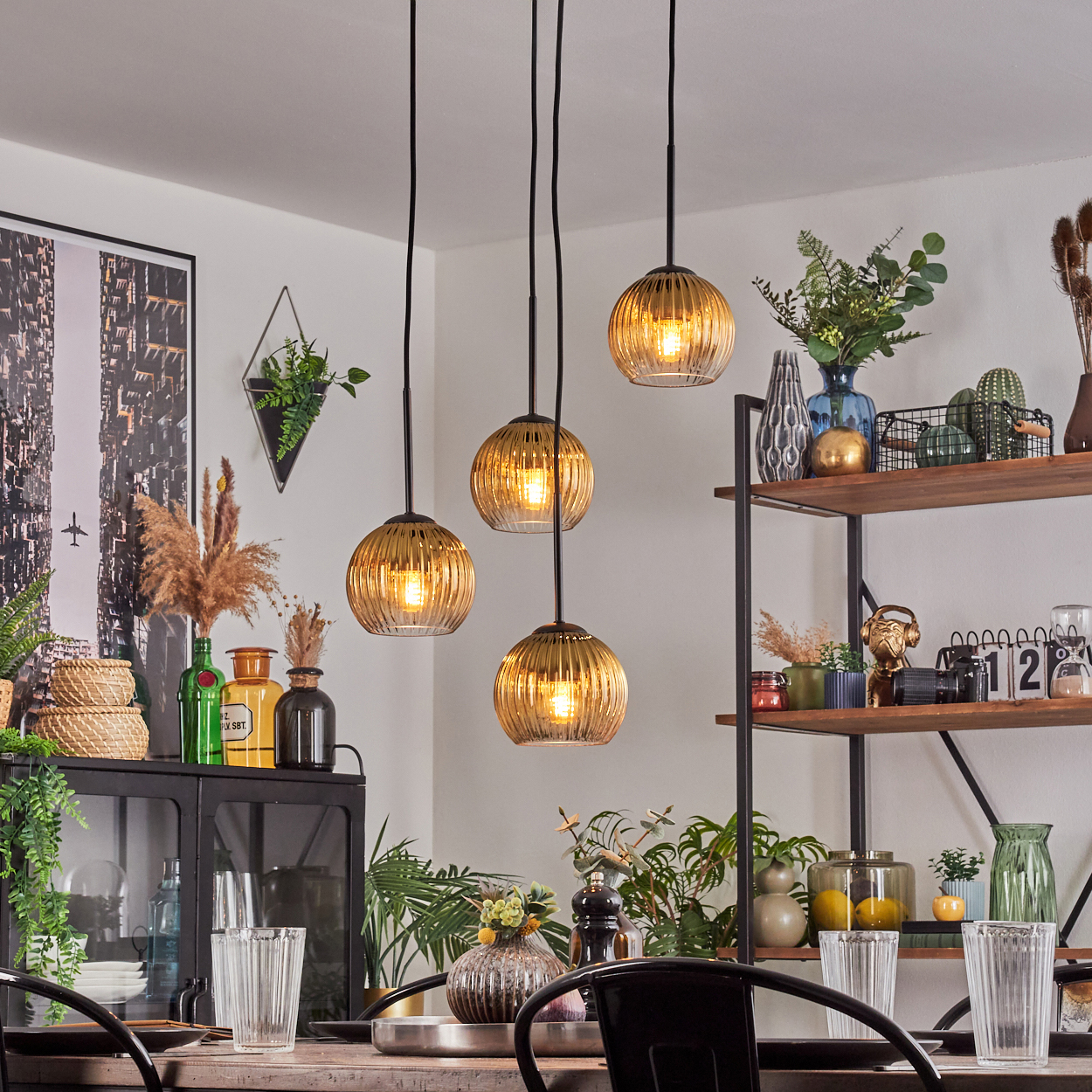 Esszimmer mit Hängelampen, Regalen mit Pflanzen und Dekoration sowie einem gedeckten Tisch.