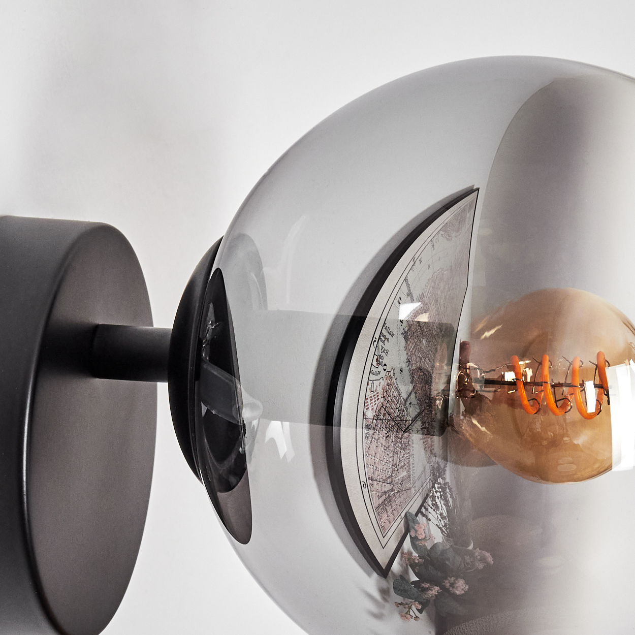 Eine moderne Wandlampe mit kugelförmigem Schirm. Im Inneren des Globus befindet sich eine Karte. Eine warme Glühbirne ist darin.