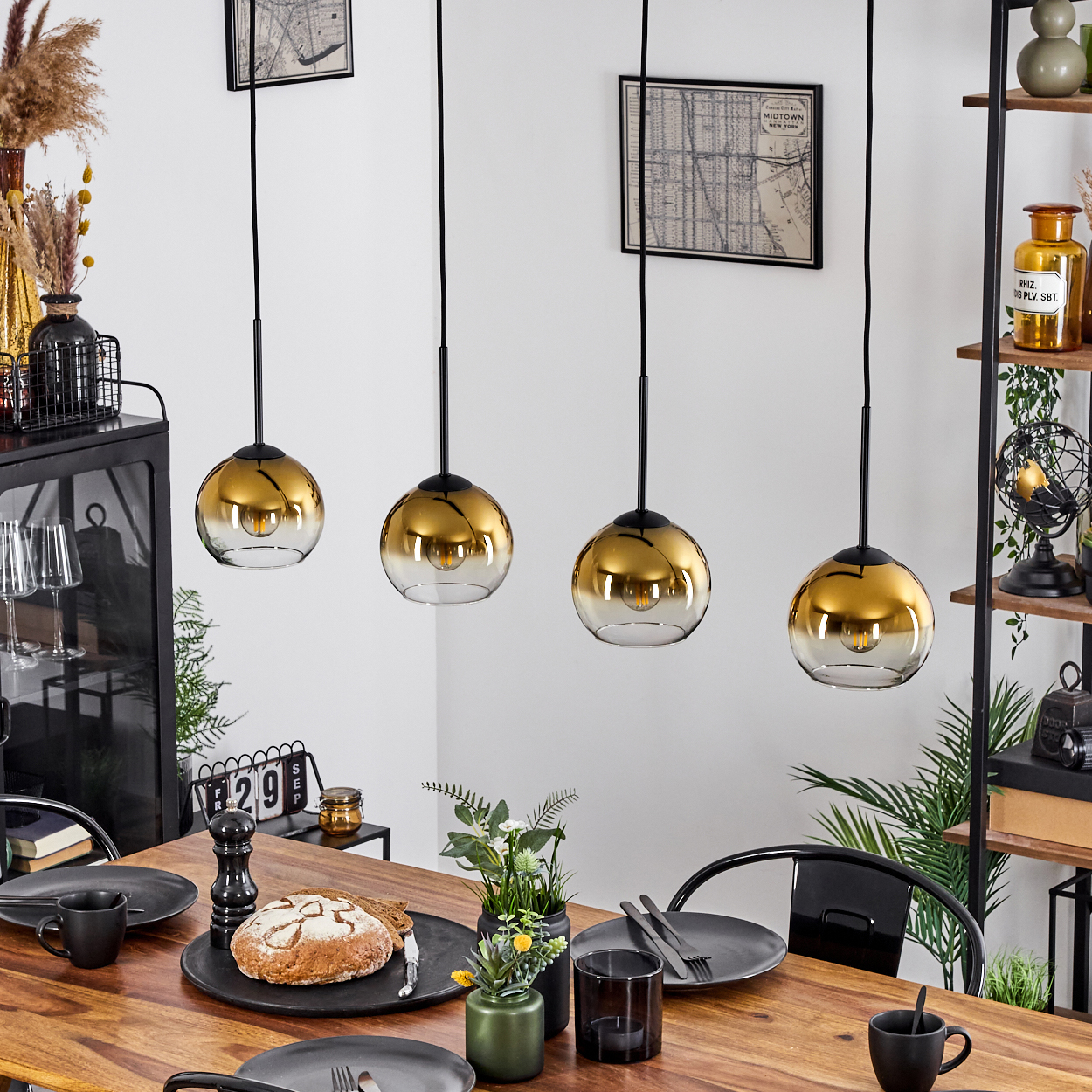 Esszimmer-Szene mit einem Holztisch, der für eine Mahlzeit gedeckt ist. Vier goldene Pendelleuchten hängen darüber. Brot, Teller und Blumen stehen auf dem Tisch.