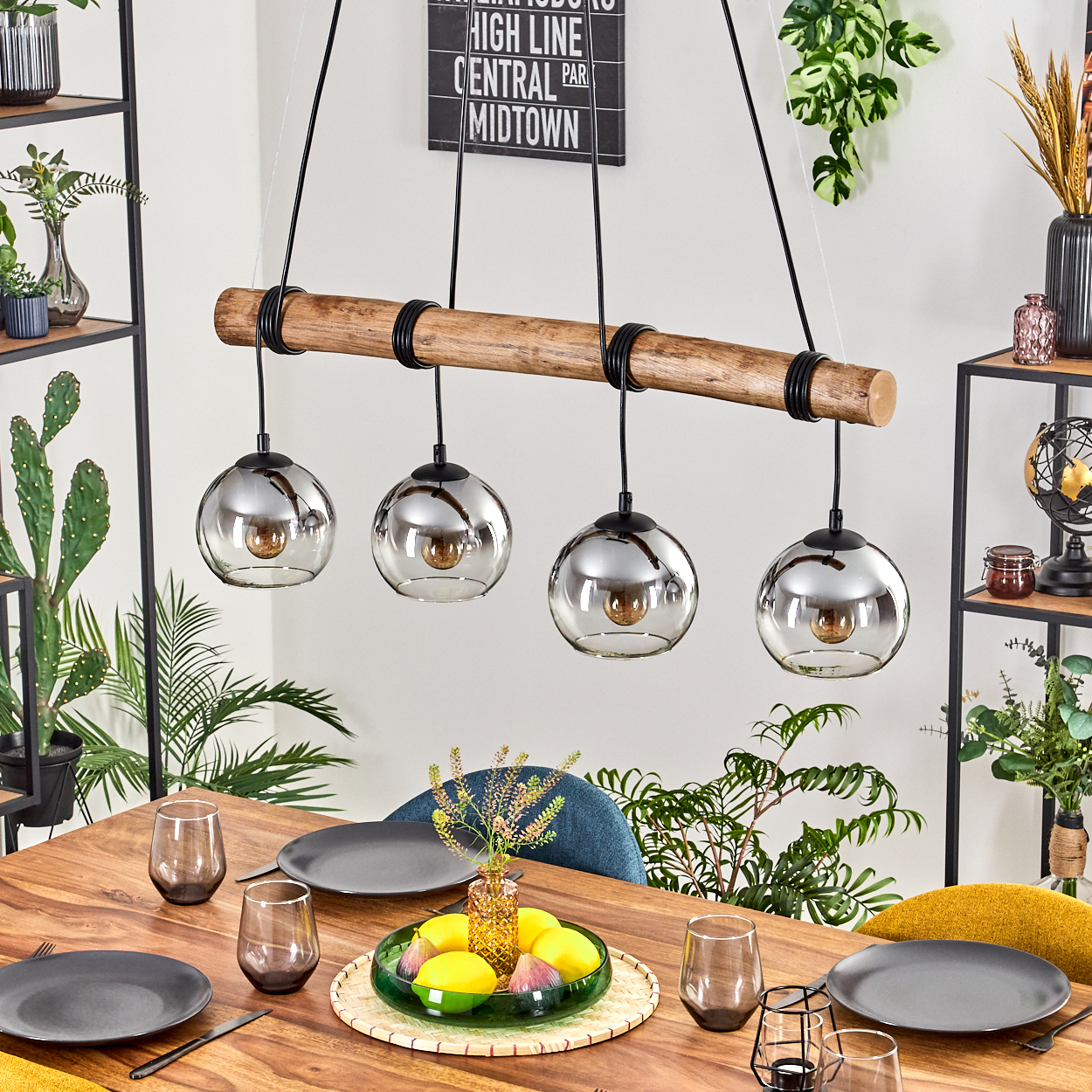 Ein Esszimmer mit Holztisch, vier Kugellampen, Tischgedeck mit Tellern und Gläsern.