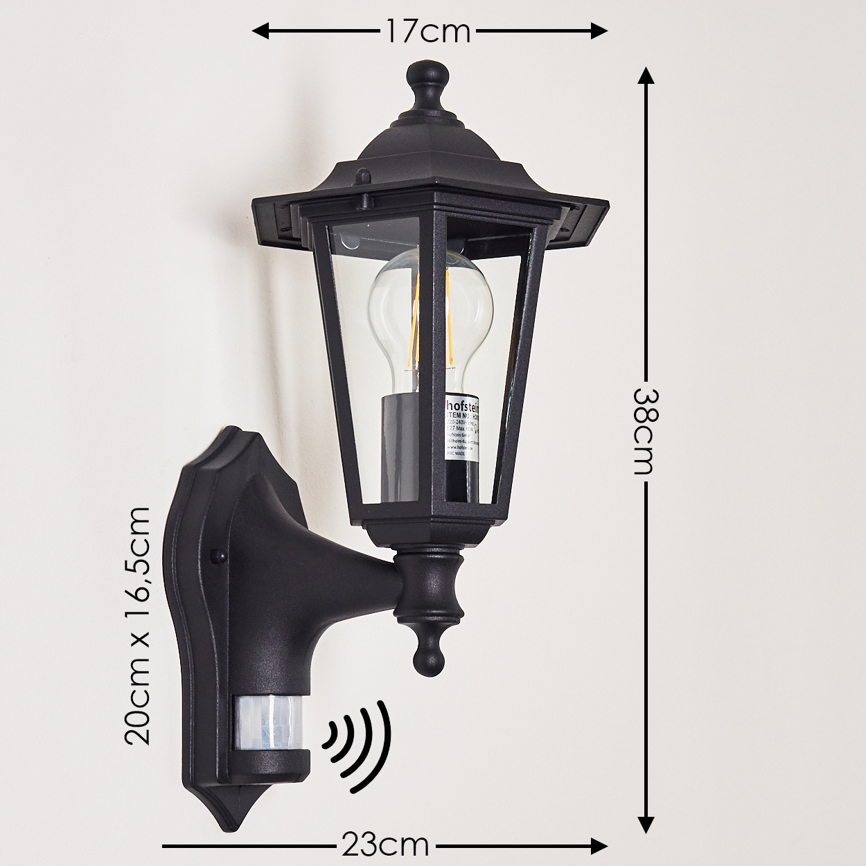 Schwarze Außenlampe an weißer Wand. Die Lampe hat ein Glasgehäuse und einen Bewegungssensor. Abmessungen sind angegeben.