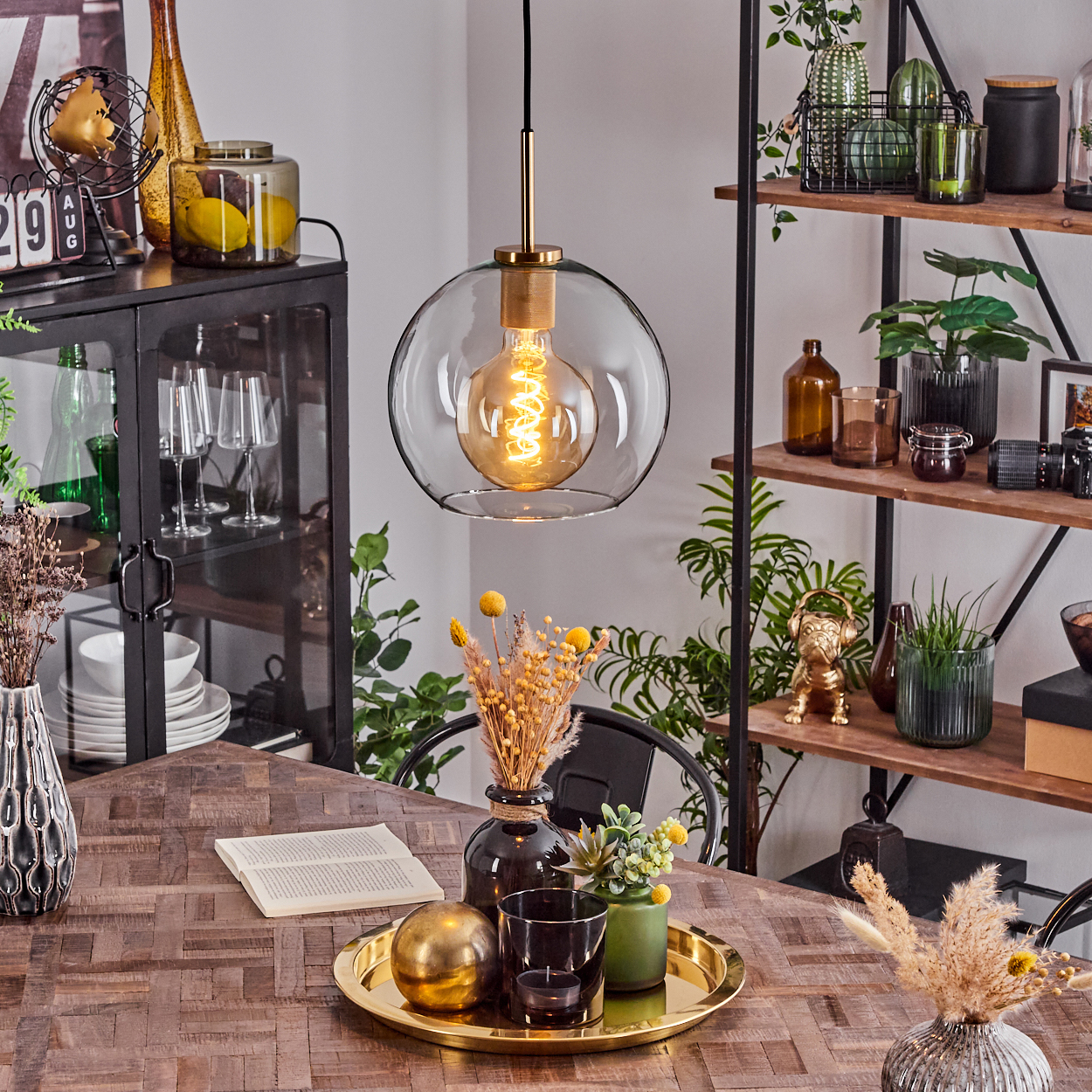 Ein Esszimmer mit Holztisch, Hängelampe und dekorativen Elementen wie Vasen und Pflanzen.