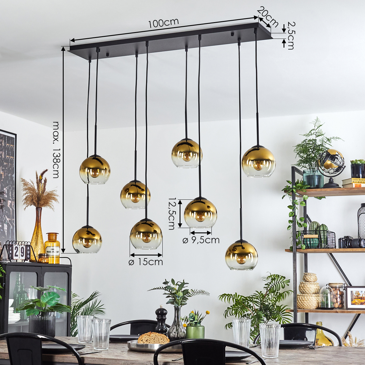 Esszimmer mit langem Tisch und Hängelampen. Die Leuchten sind gold und Glas, mit schwarzer Halterung. Pflanzen und Dekoration vorhanden.