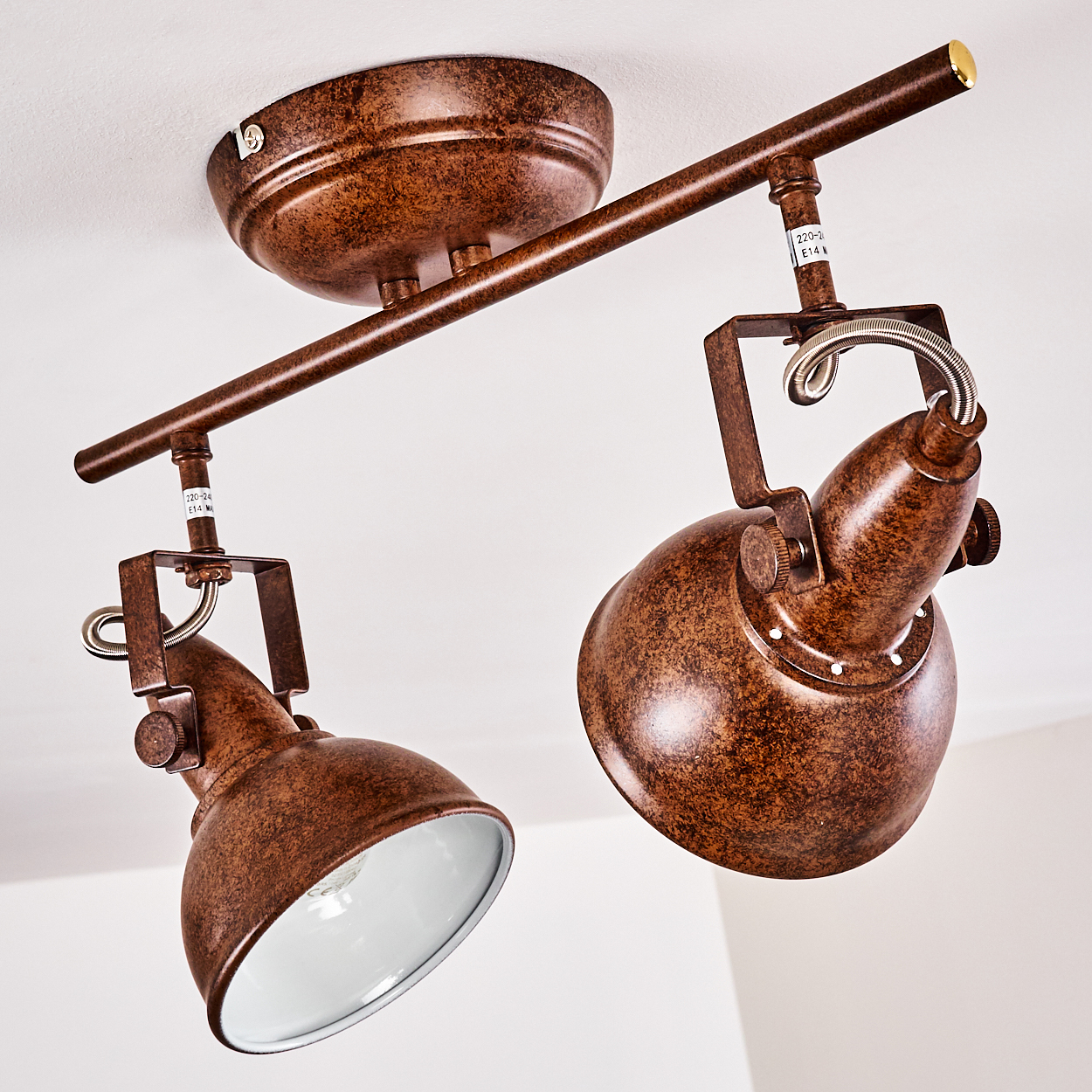 Zwei braune Scheinwerfer im Retro-Stil, die an einer weißen Decke montiert sind. Jede Lampe hat einen weißen Innenraum und ein braunes, strukturiertes Äußeres.