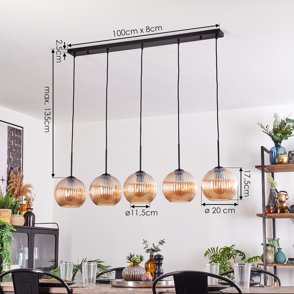 Ein Esszimmer mit einem langen Holztisch, fünf Pendelleuchten und einem Regal mit Vasen und Dekorationen im Hintergrund.
