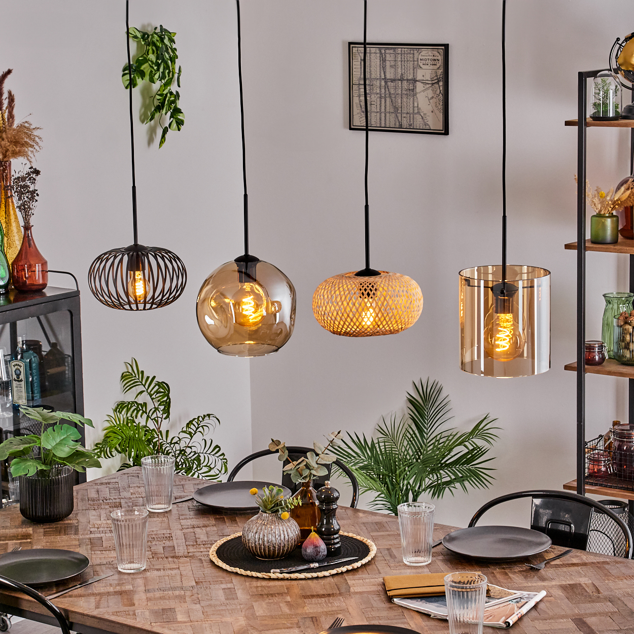 Esszimmer mit Holztisch, vier Hängelampen, Pflanzen, Tellern, Gläsern. Dekoration auf Regalen und Tischmitte.