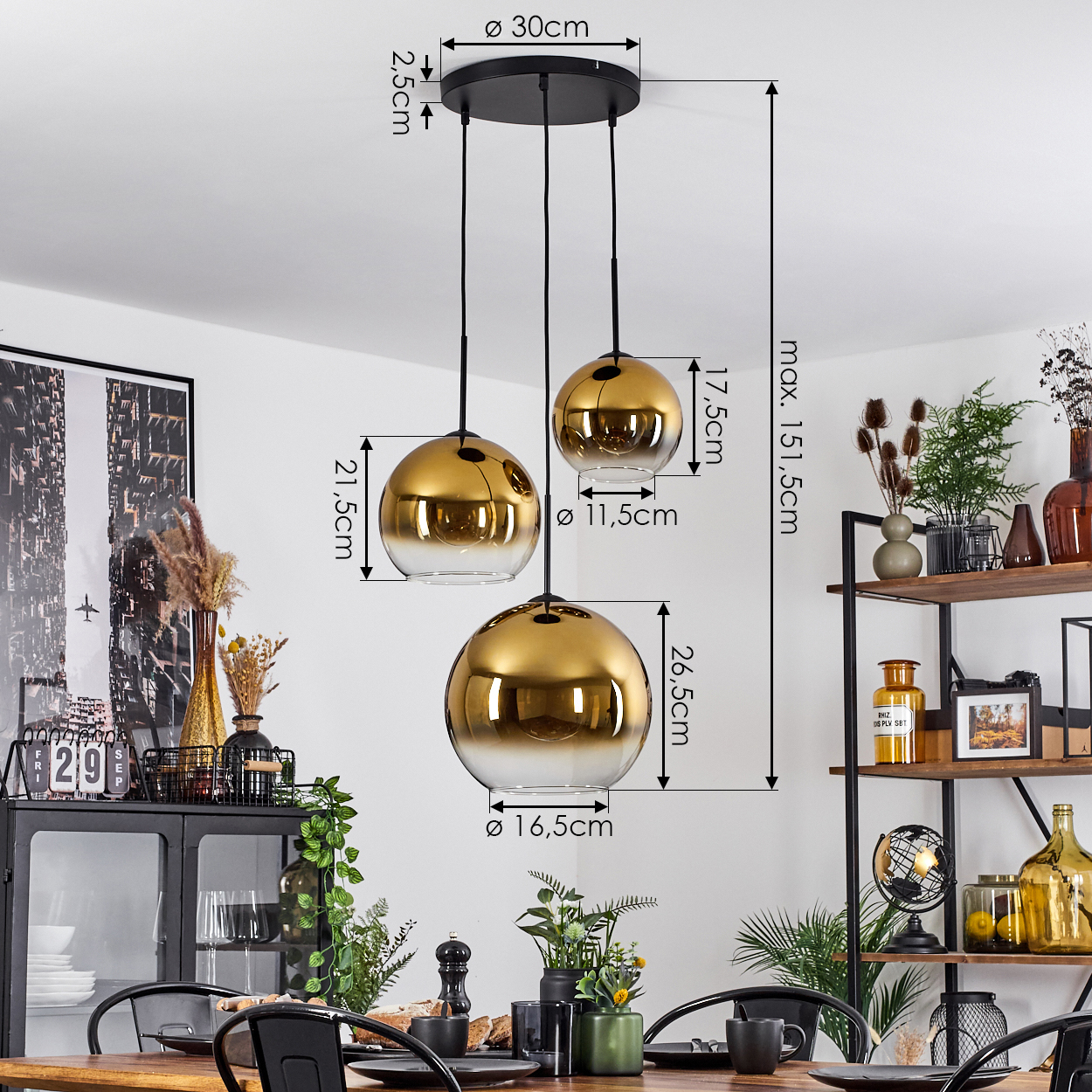 Drei gold- und gläserne Pendelleuchten hängen über einem Esstisch. Maße werden angezeigt. Im Hintergrund befindet sich ein Regal mit Dekoration.