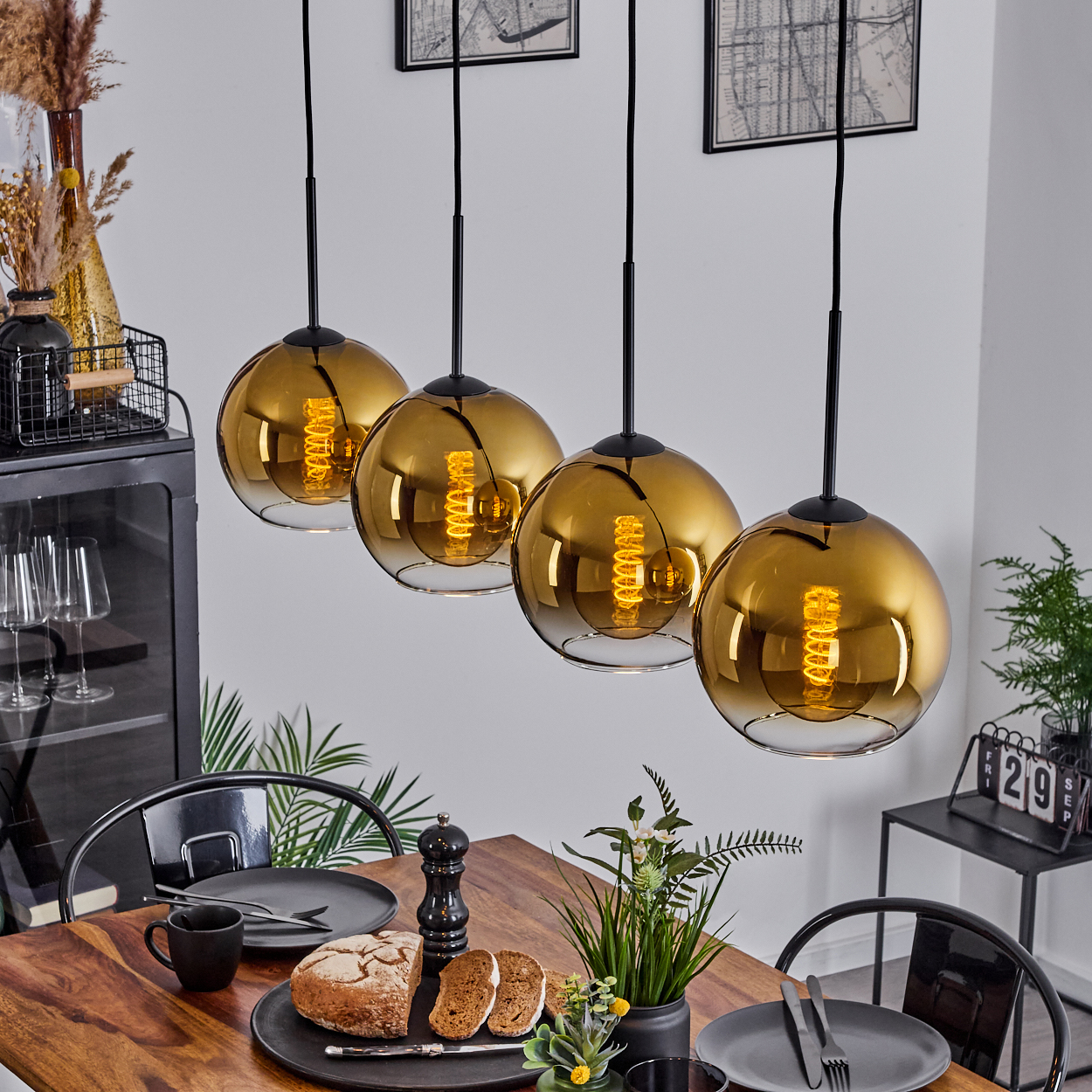 Esszimmer mit vier goldenen Kugelleuchten, einem Holztisch mit Gedeck und dekorativen Elementen.