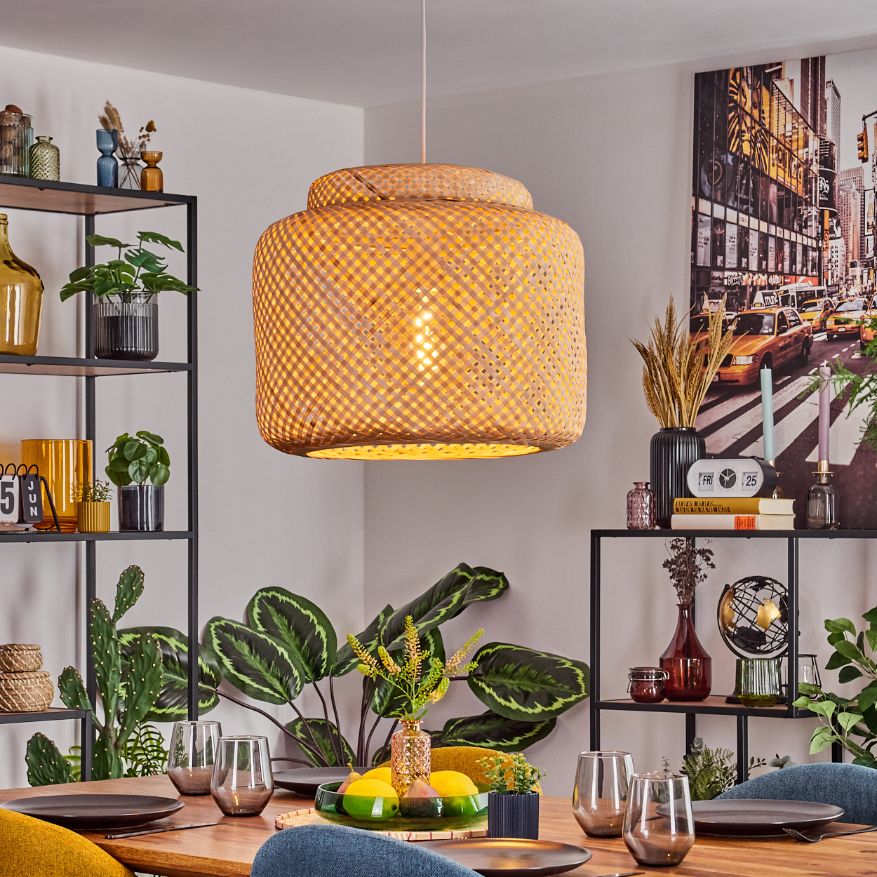 Esszimmer mit gewebtem Lampenschirm, gedecktem Tisch, Pflanzen, Regalen mit Dekoration und einem Stadtbildgemälde im Hintergrund.