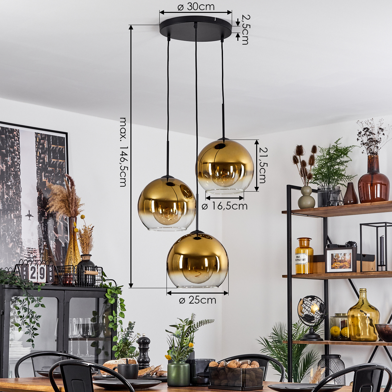 Drei goldene Pendelleuchten hängen über einem Tisch, der für eine Mahlzeit gedeckt ist. Regale rechts halten Dekorationen. Maße sind ebenfalls angegeben.