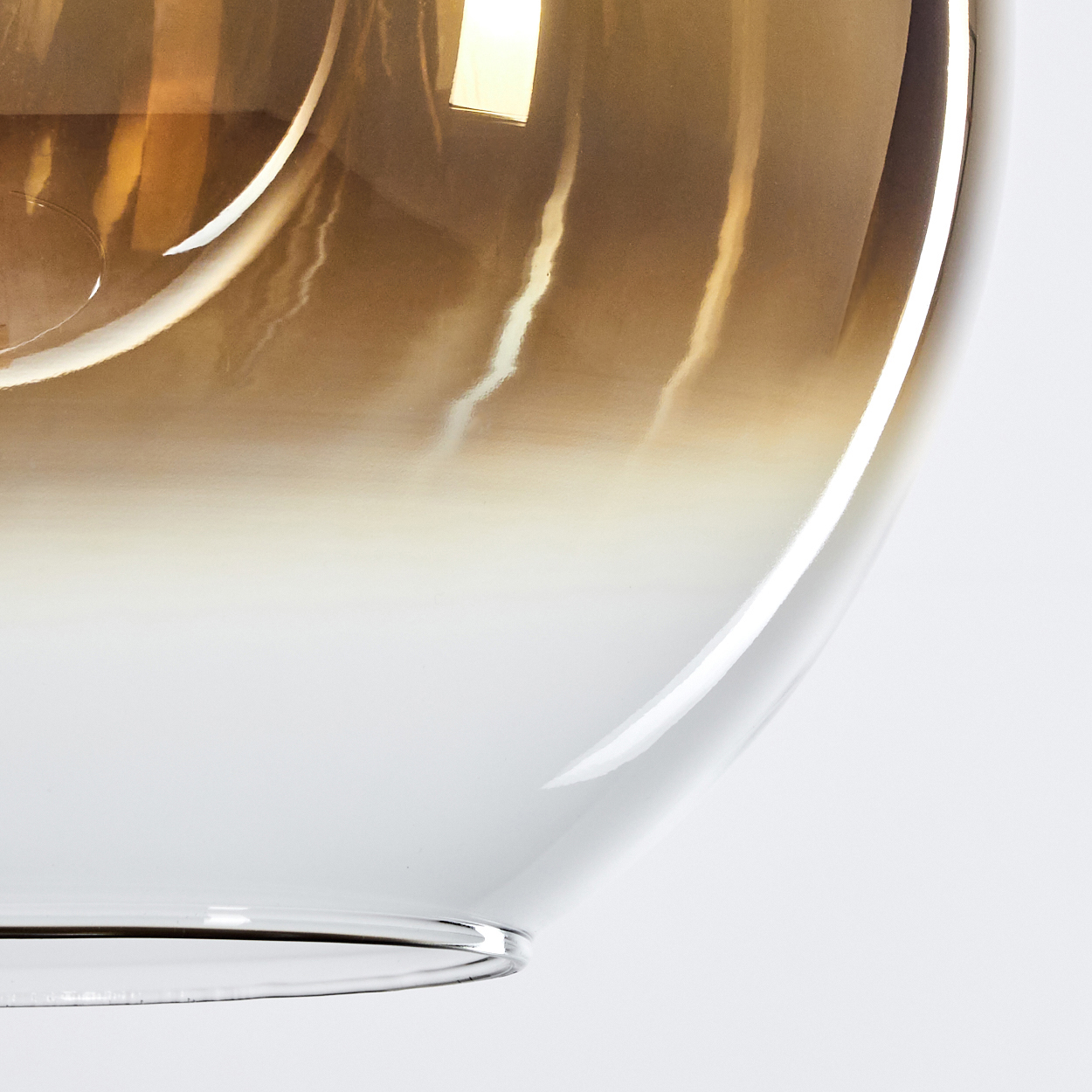 Nahaufnahme einer Glasleuchte. Die Oberseite ist bernsteinfarben und geht in Weiß über. Das Glas wölbt sich und reflektiert Licht.