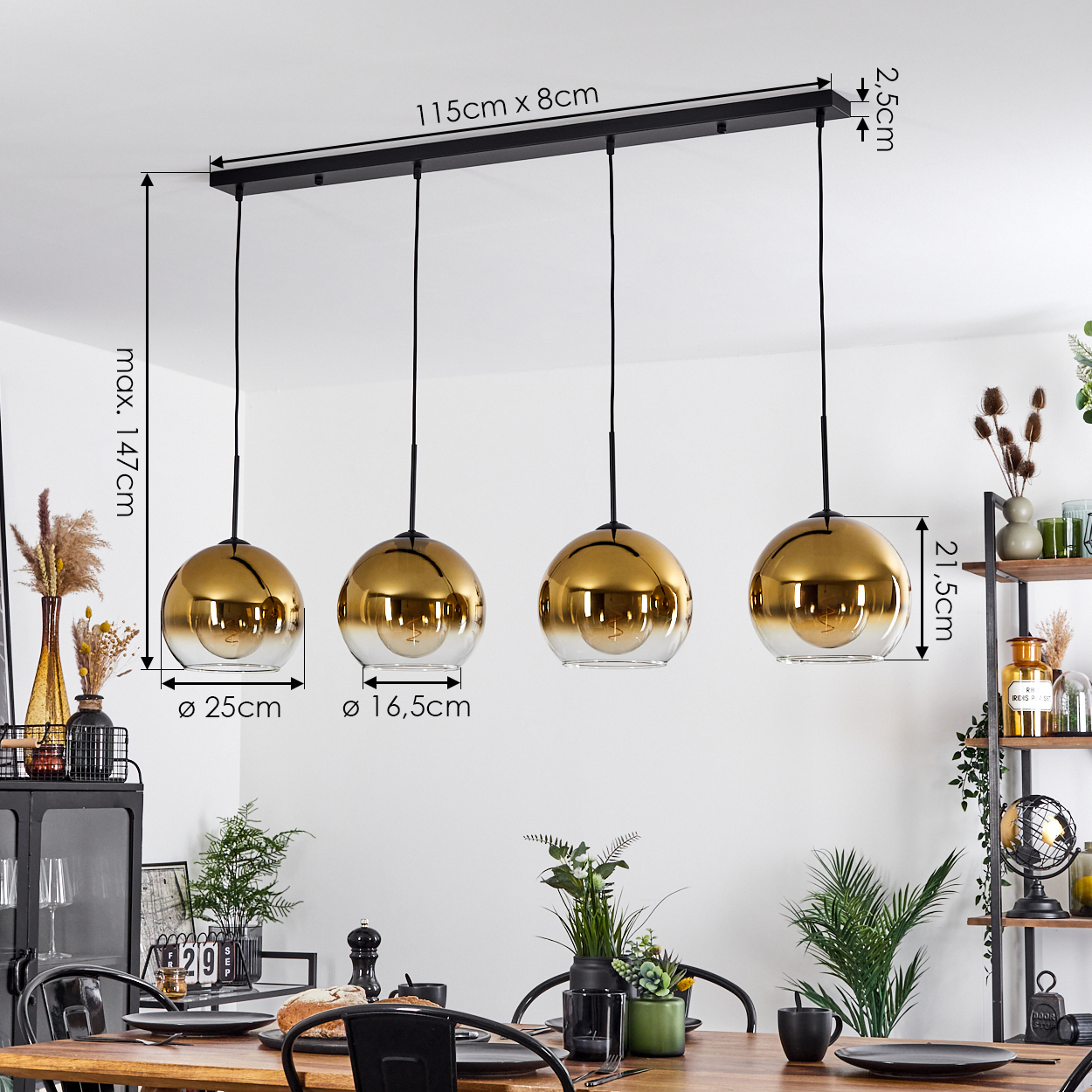 Ein Esszimmer mit einem Holztisch, mit einer schwarzen Deckenleuchte mit vier gold- und glaskugelförmigen Lampen.