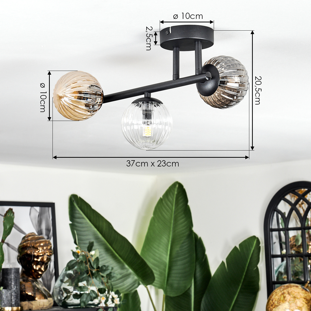 Eine moderne Deckenlampe mit drei kugelförmigen Schirmen. Die Lampe ist schwarz, die Schirme sind gold und klar.