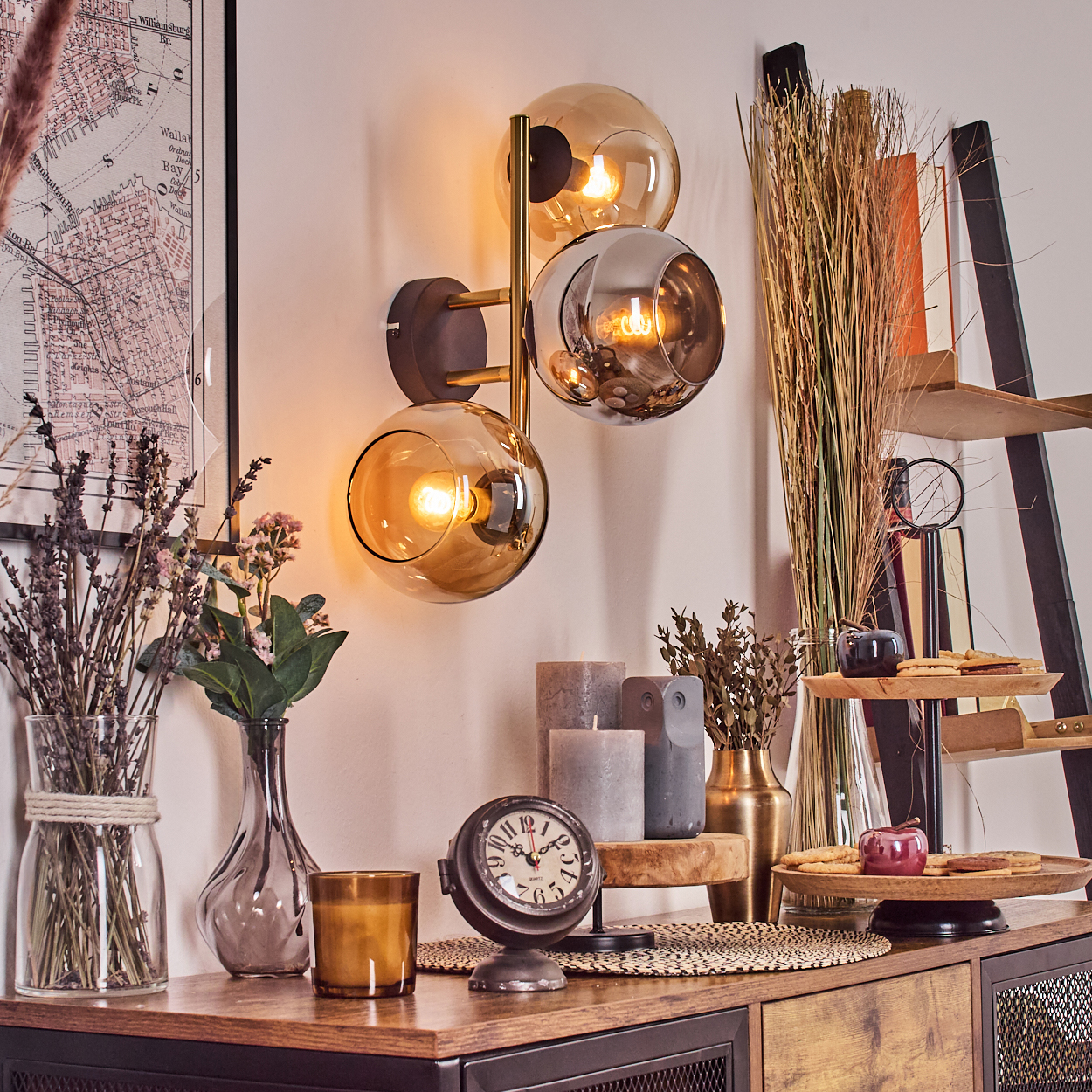Ein Raum mit Wandlampe, Vasen, Kerzen und Uhr auf einem Holztisch. Eine Karte ist an der Wand sichtbar.
