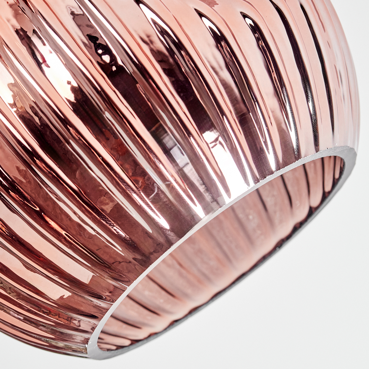Nahaufnahme eines roségoldenen, gerippten Glasschirmes vor weißem Hintergrund. Der Schirm hat einen metallischen Glanz und eine runde Form.