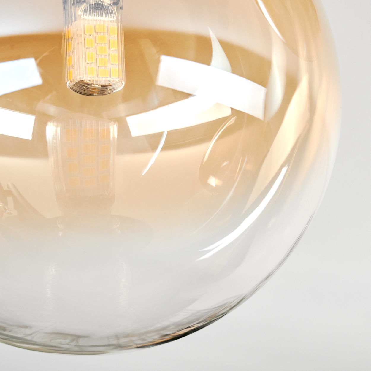 Nahaufnahme einer Glühbirne mit gelb getöntem Glaskolben. Innen ist ein kleines rechteckiges LED-Licht zu sehen.