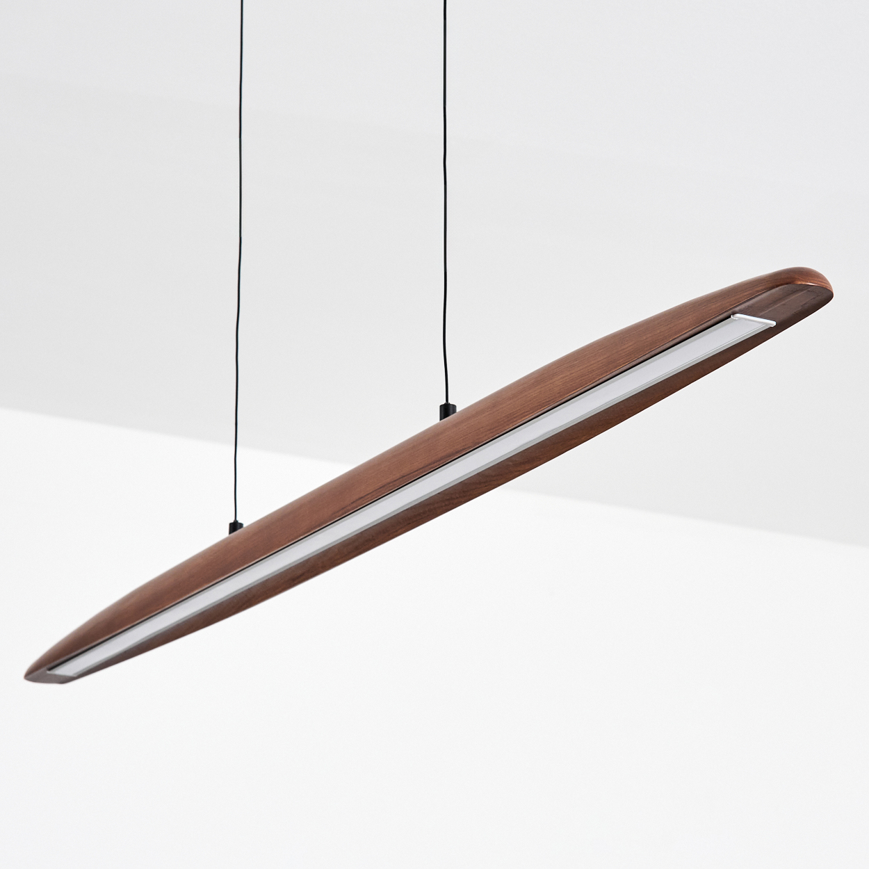 Eine moderne Pendelleuchte aus Holz hängt von der Decke. Es ist ein langes, schlankes Design mit hellem, weißem Licht.