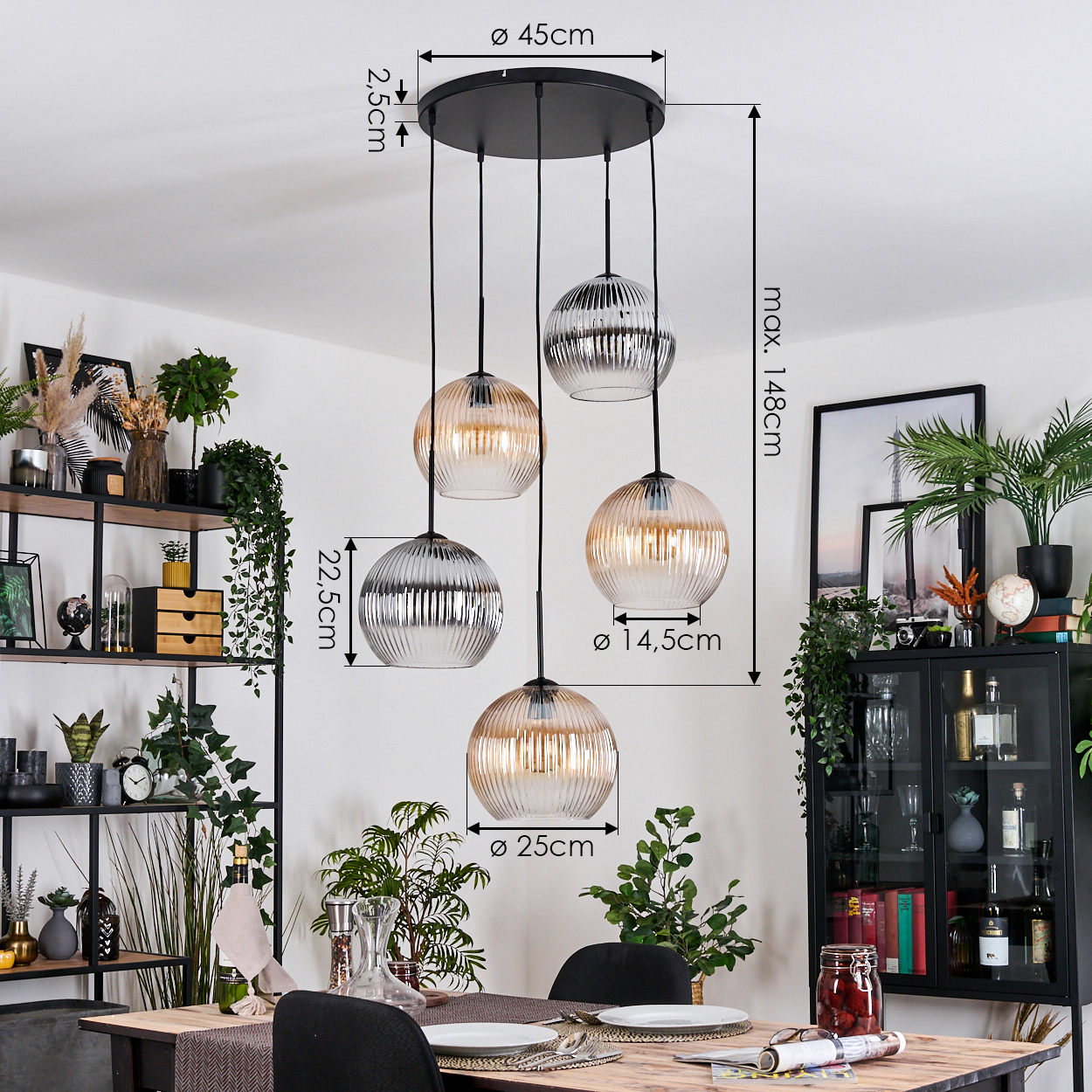 Ein Esszimmer mit Hängelampen. Die Lampen haben Glaskugeln. Es gibt einen Tisch, der für eine Mahlzeit gedeckt ist. Pflanzen sind im Raum platziert.
