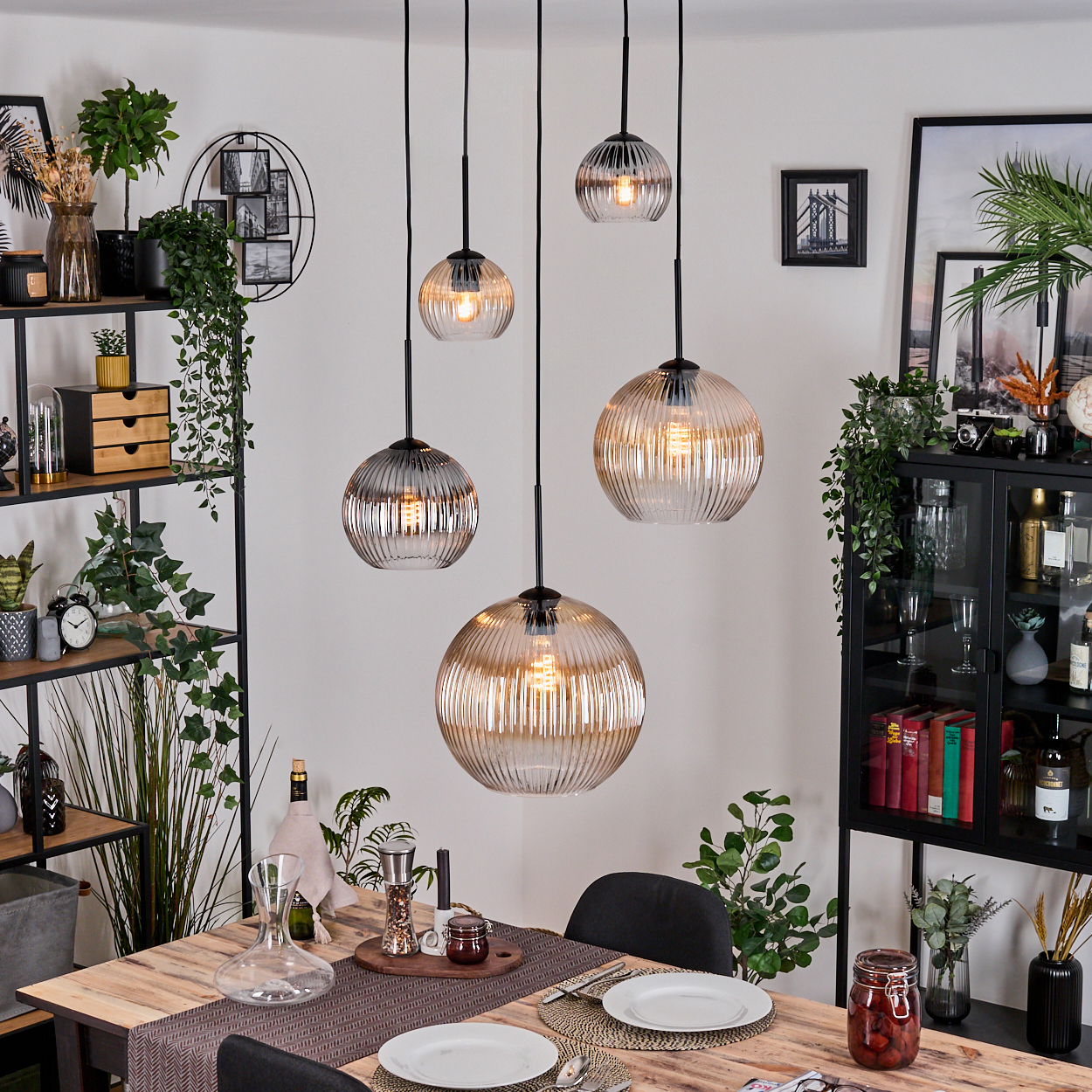 Esszimmer mit Holztisch, Glaslampen, Regalen und einem schwarzen Schrank. Tisch mit Tellern und einem Glas mit Essen. Pflanzen dekorieren.