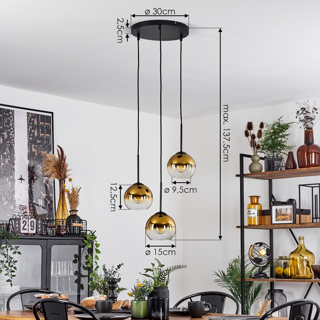Drei gold- und gläserne Pendelleuchten hängen von einer schwarzen Deckenplatte. Abmessungen sind beschriftet. Ein Esszimmer ist sichtbar.