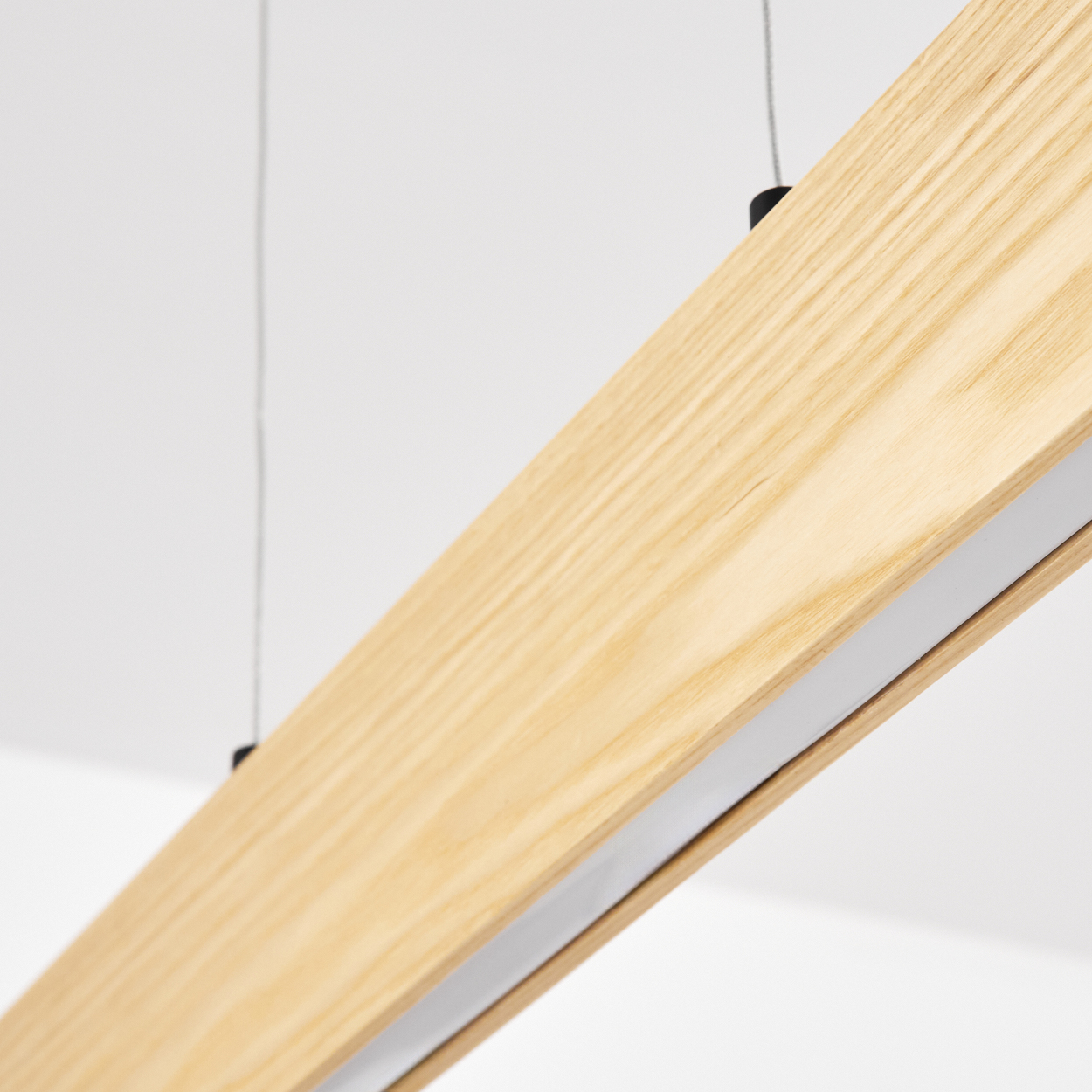 Nahaufnahme einer hängenden Holzbalken-Leuchte. Das Holz ist hellbraun mit einem weißen Streifen.