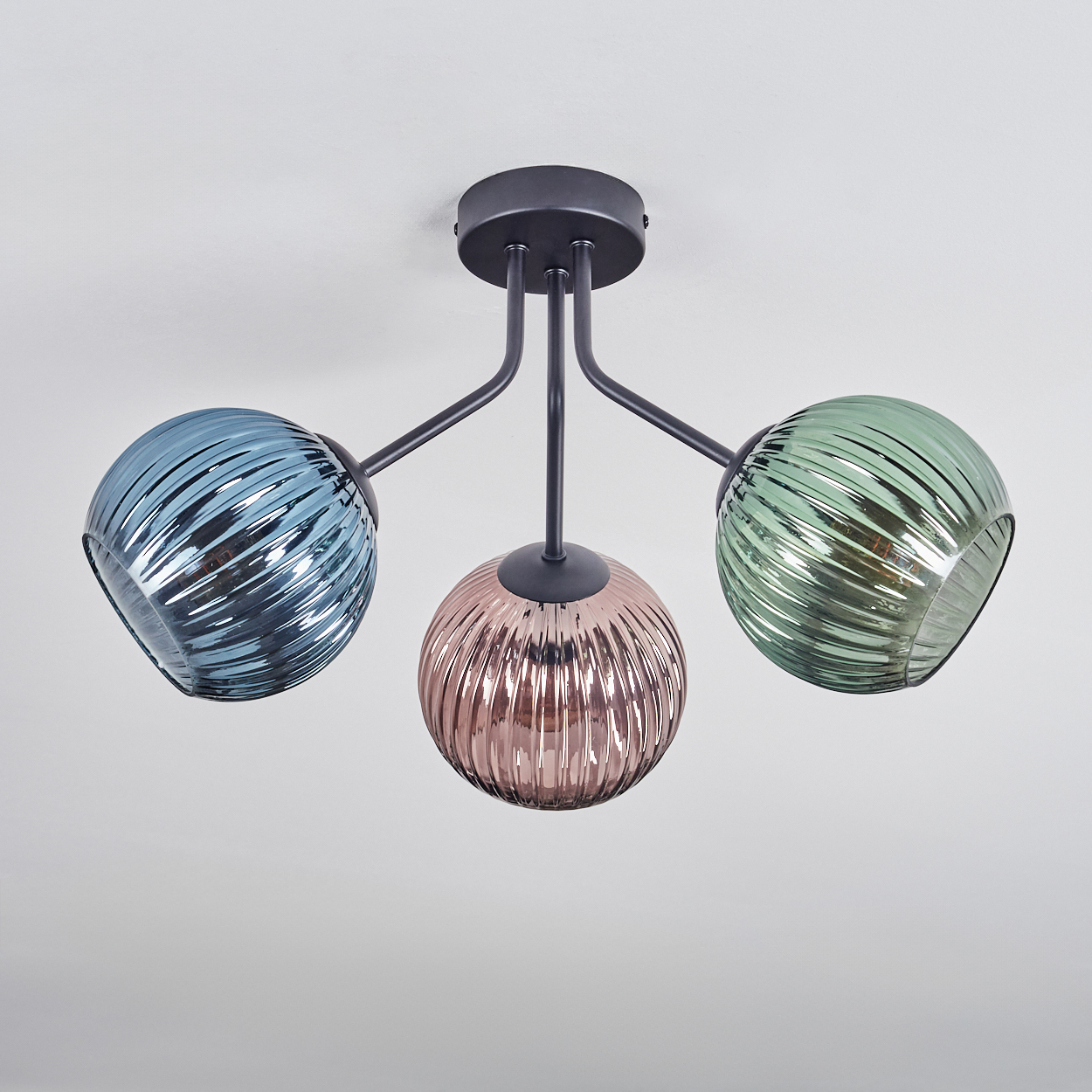 Eine moderne Deckenlampe mit drei kugelförmigen Schirmen in Blau, Rosa und Grün. Die Schirme haben ein geripptes Design.