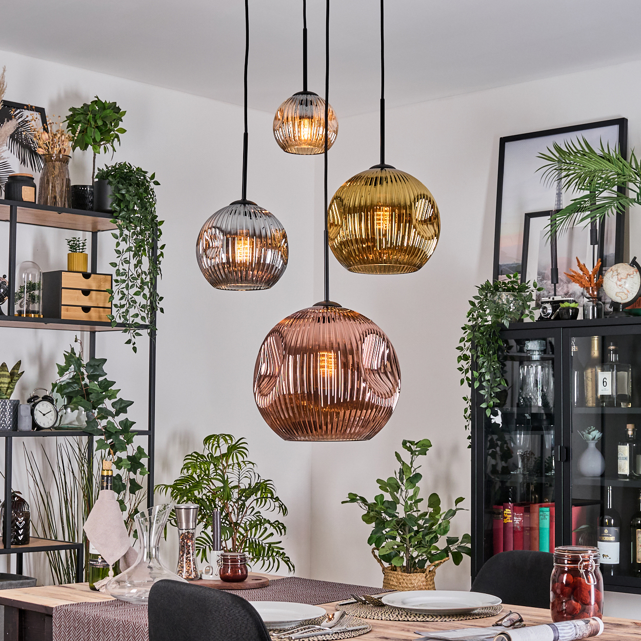 Esszimmer mit Hängelampen, Pflanzen, einem Tisch mit Tellern und einem Schrank mit Gegenständen.