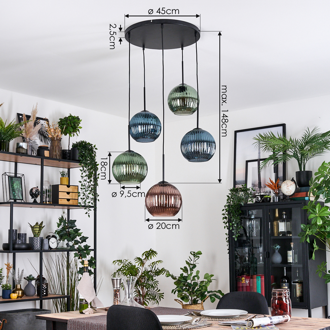 Fünf Pendelleuchten aus Glas hängen von der Decke. Darunter ist ein Esstisch mit Pflanzen und Dekoration im Hintergrund.