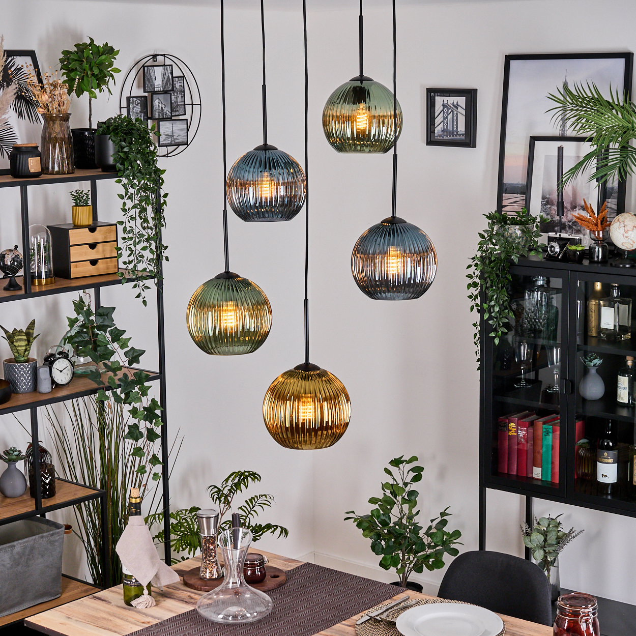 Esszimmer mit hängenden Kugelleuchten, Regalen, einem Tisch mit Geschirr und dekorativen Pflanzen. Der Raum ist gut beleuchtet.