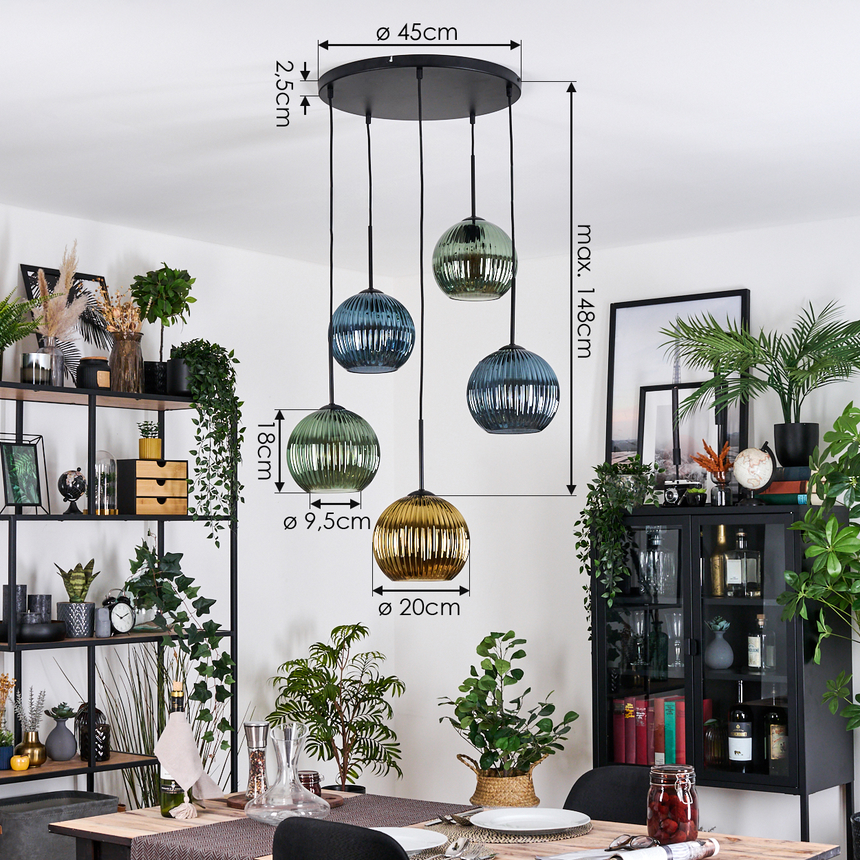 Ein Esszimmer mit Hängeleuchten. Die Leuchten haben Glasschirme in verschiedenen Farben. Pflanzen und ein Schrank sind im Hintergrund.