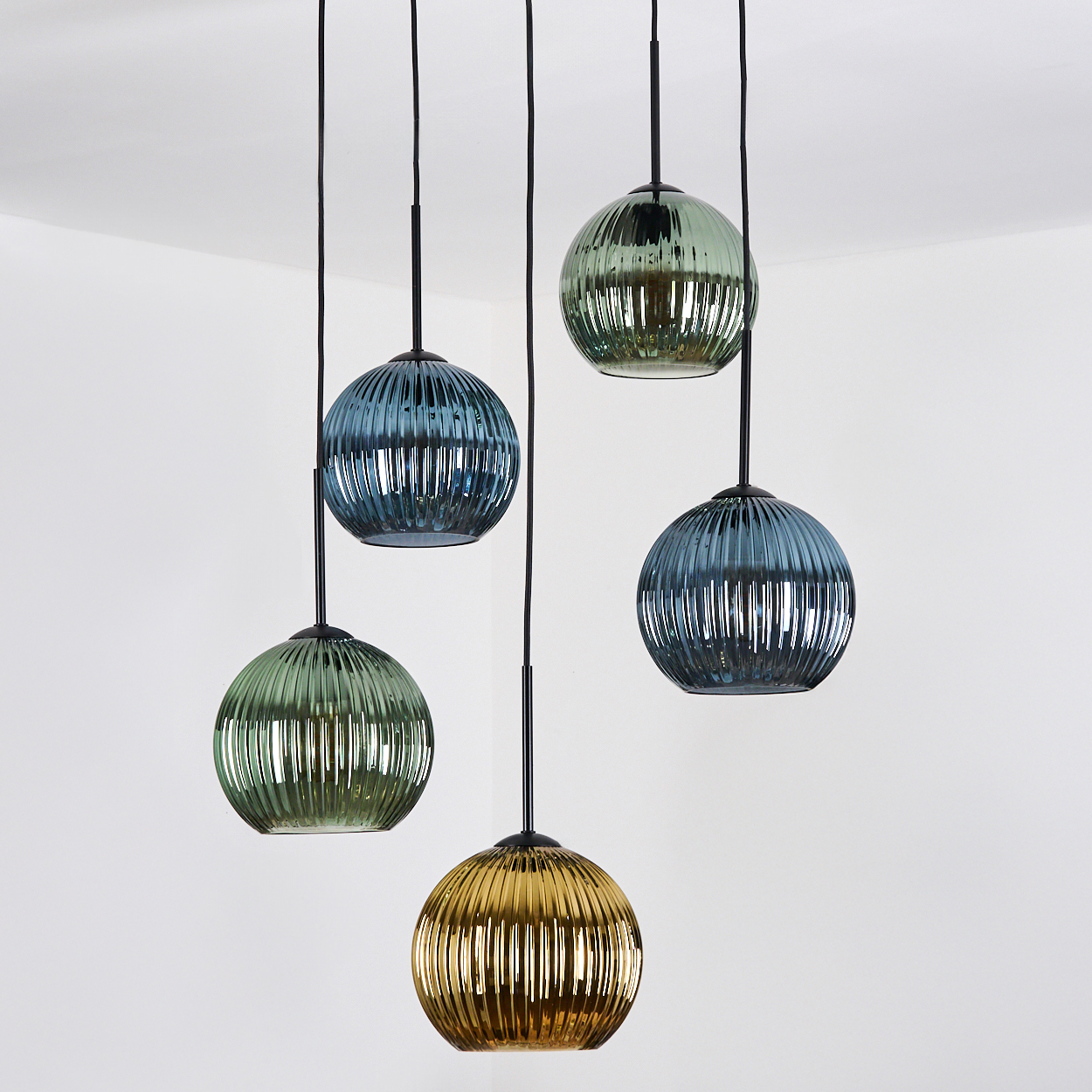 Fünf kugelförmige Pendelleuchten mit strukturiertem Glas. Farben sind Blau, Grün und Gold vor weißem Hintergrund.